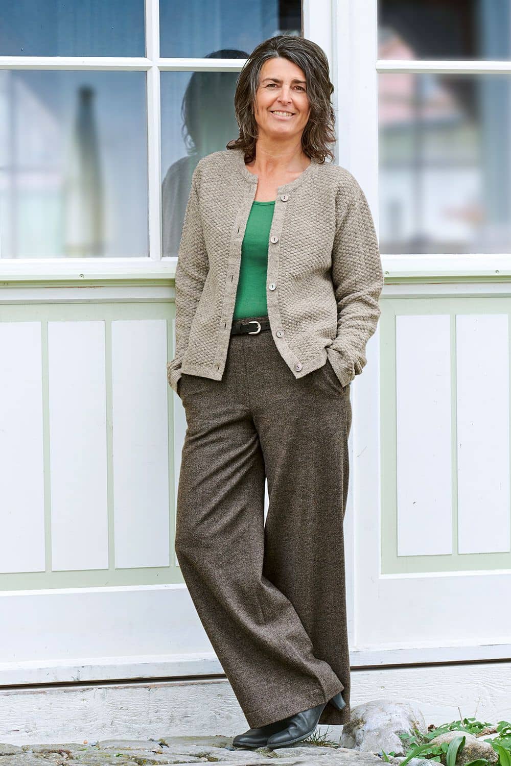 Damen-Wollhose Frau trägt braunmelierte Finkhof Wahllose aus bio Wolle (kbT) mit grünem Shirt und hellbrauner Strickjacke