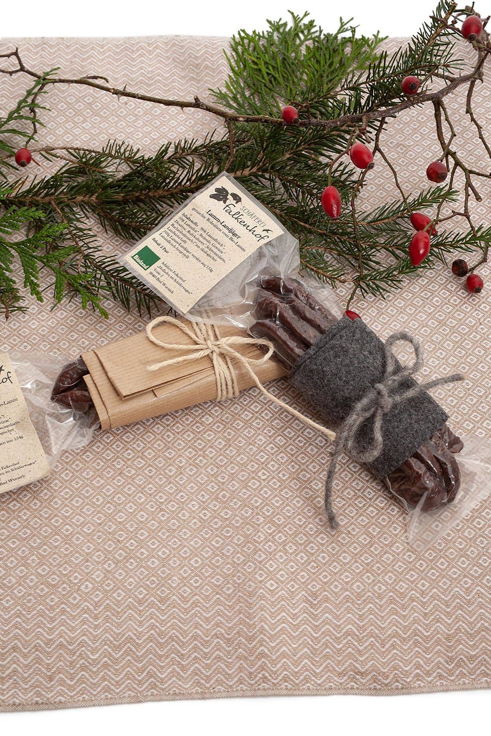 verpackte Bio Lammjäger vom Finkhof auf weihnachtlichem Stimmungsbild mit Hagebuttenstrauch