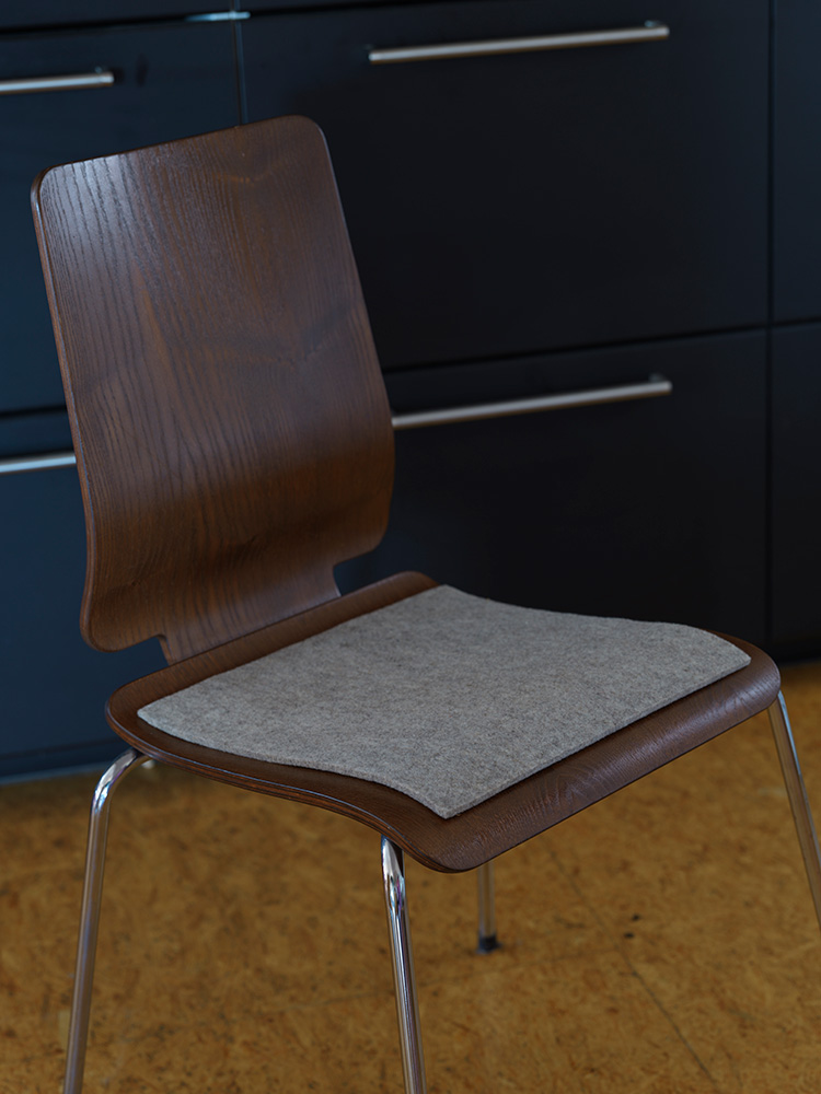 graue eckige Finkhof Sitzauflage aus bio Wolle (kbT) auf einem Holzstuhl