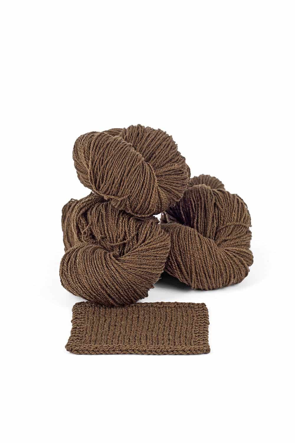 Finkhof Merinowolle dünn gefärbt walnuss braune dünne Finkhof Merinowolle aus bio Wolle (kbT) mit Strickstück davor, weißer Untergrund