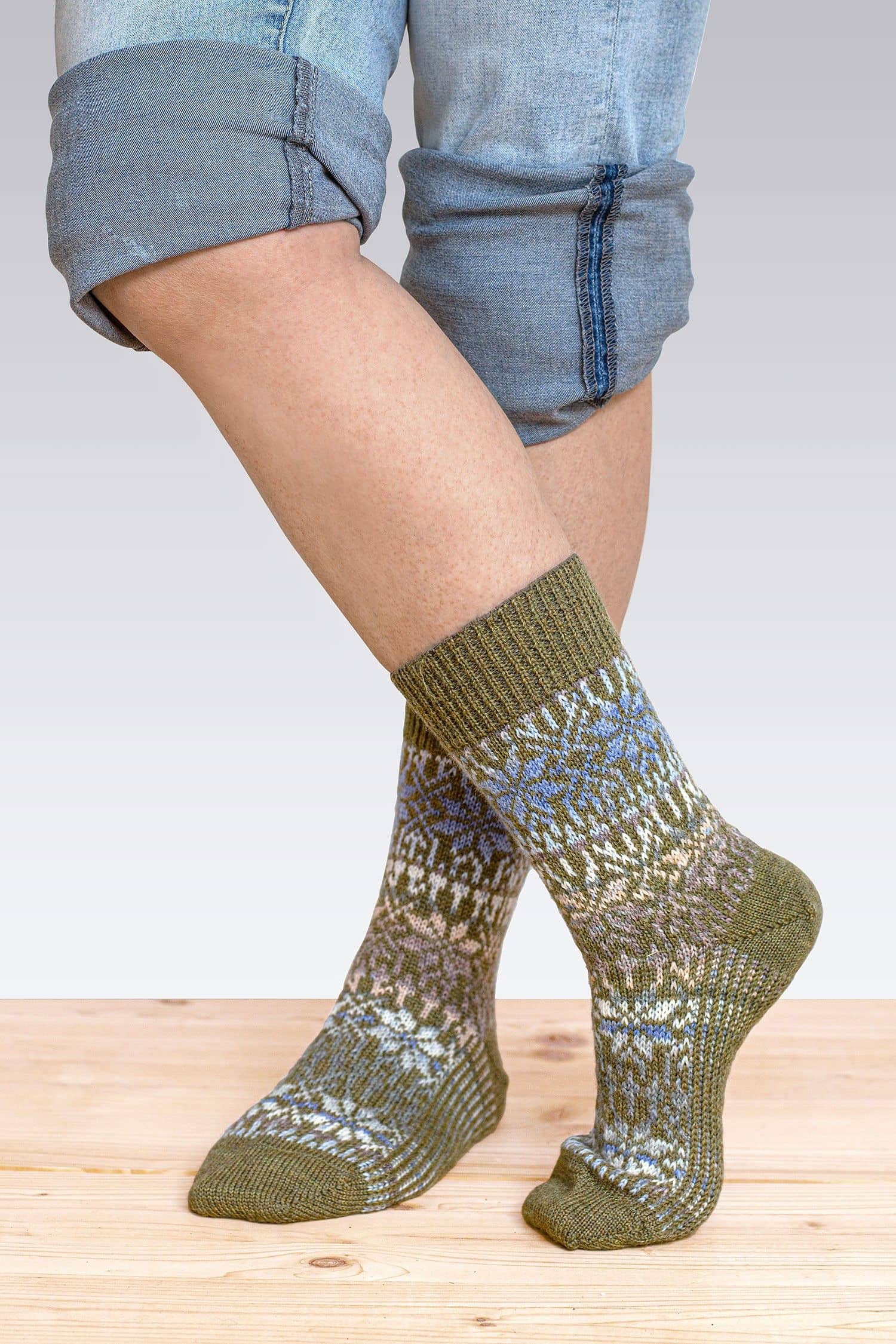 Person mit hochgekrempelter Jeans trägt olivegrüne Norwegersocken aus bio Wolle (kbT), von vorne