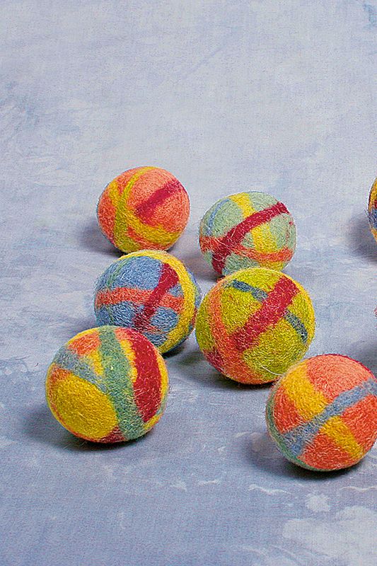 Rasselball Wollbälle in verschiedenen Kombinationen aus bio Wolle (kbT) auf blauem Hintergrund verteilt