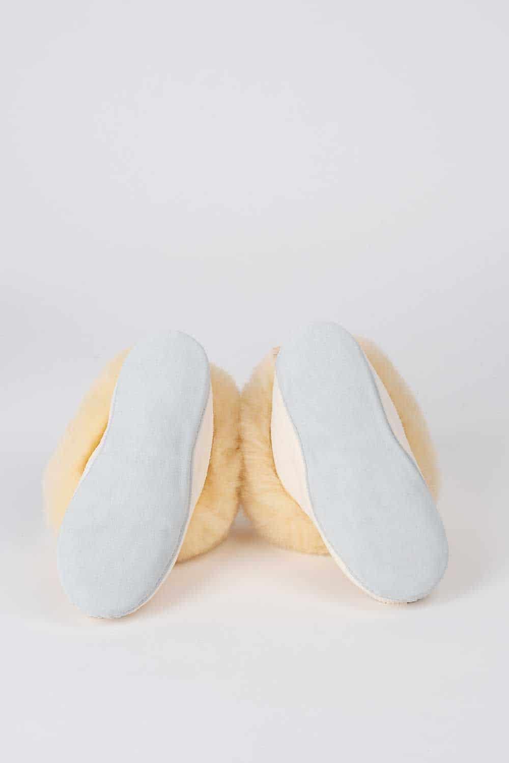 Paar weiße Finkhof Fellschuhe aus Schaffell und Rindsleder mit Sohle nach vorne hingelegt