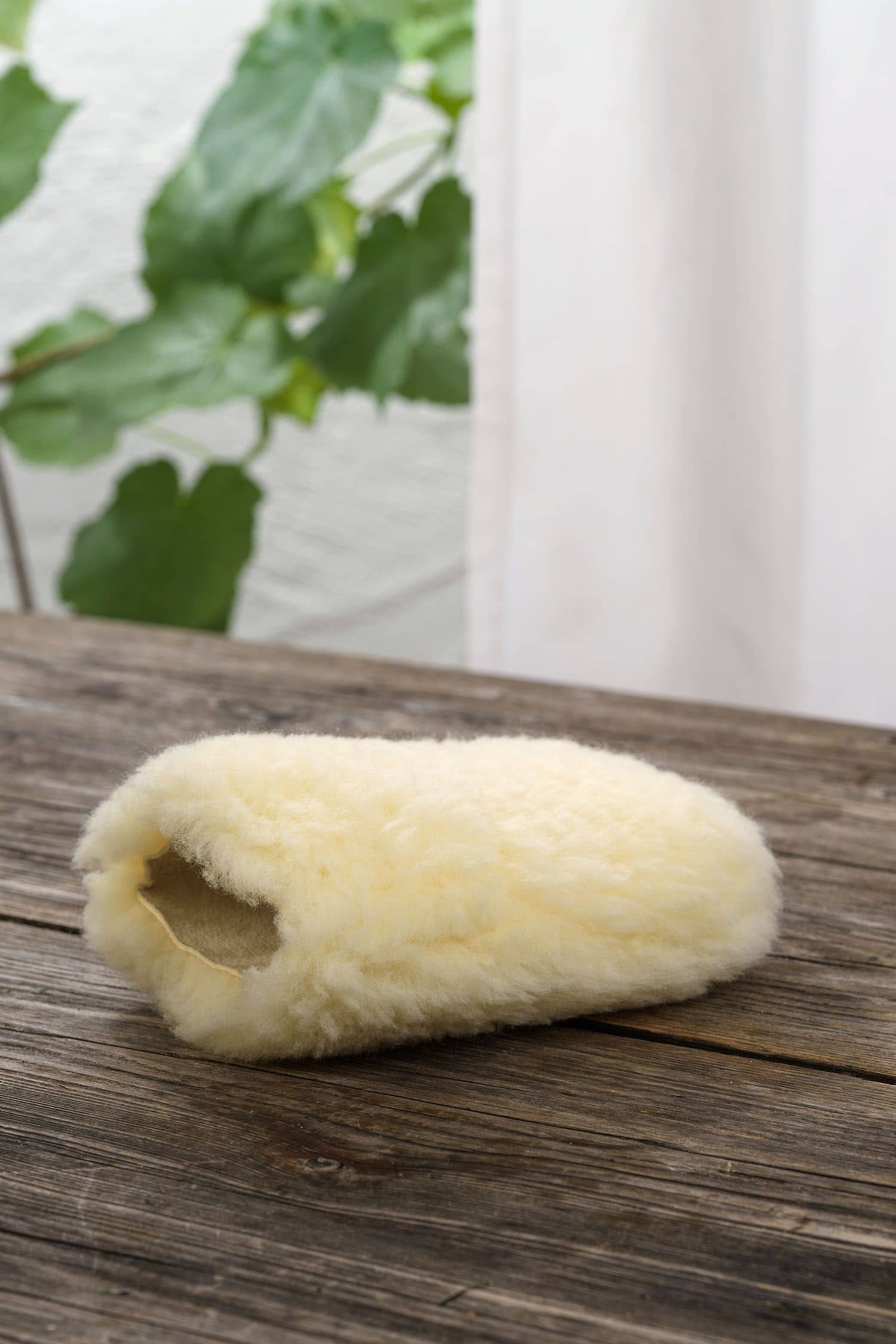 gelblicher Staubhandschuh vom Finkhof aus relugan gegerbtem Schafell auf braunem Holzboden