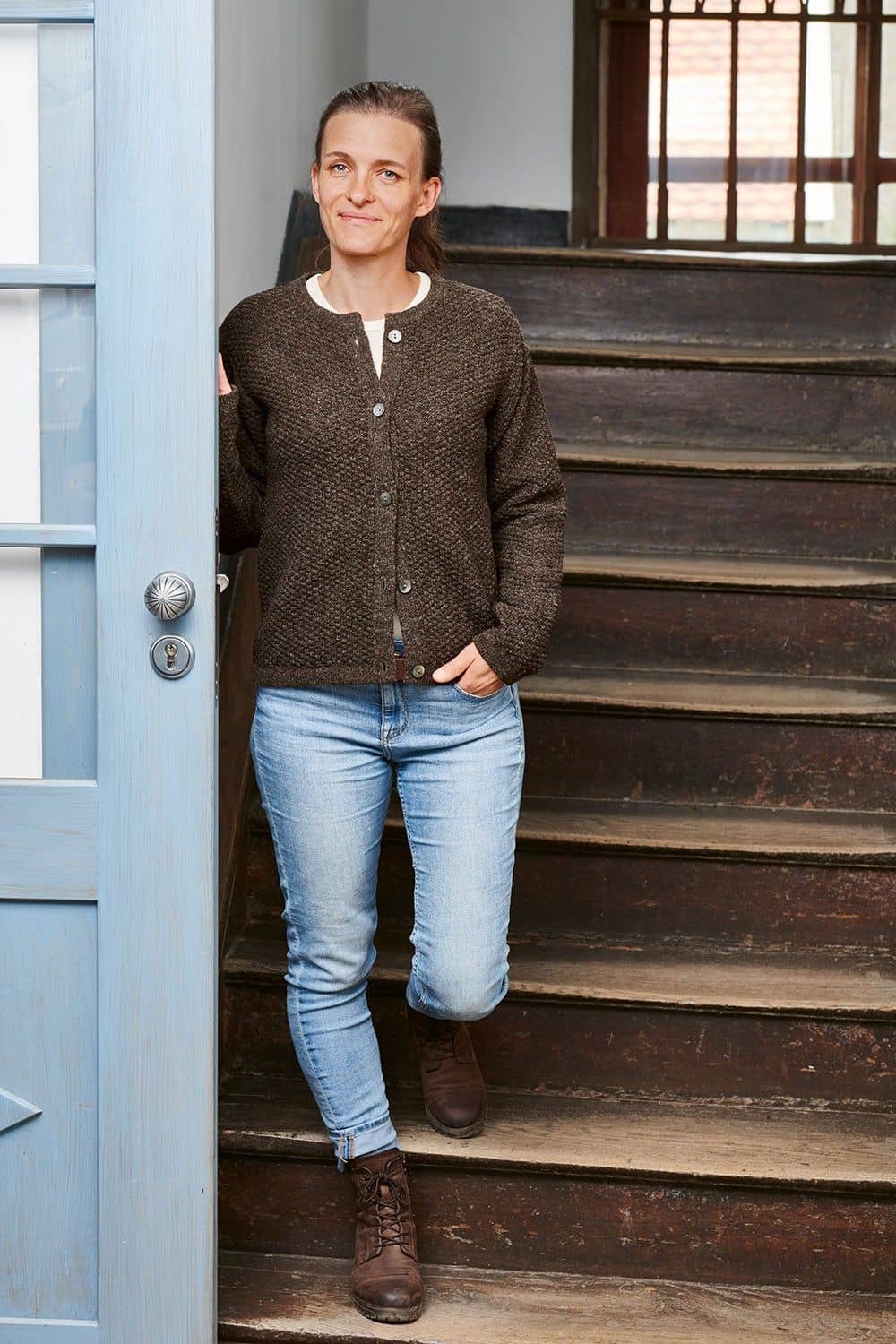 Finkhof-Strukturjacke braun Gr. S Frau kommt Treppe hinunter und trägt Jeans und braune Finkhof Strukturjacke aus bio Wolle (kbT)