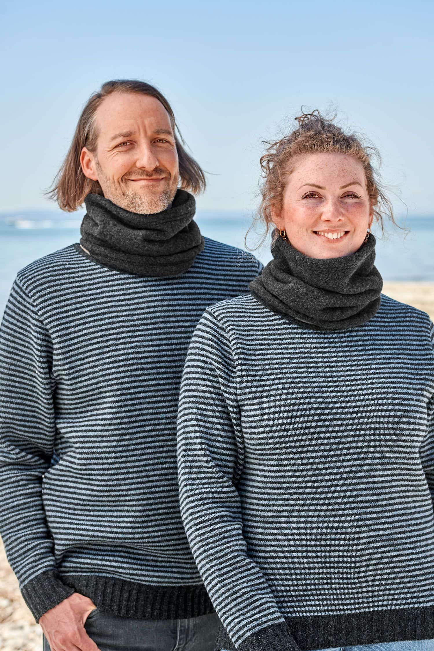 Mann und Frau mit Streifenpullis tragen anthrazitfarbene Schlupfschals aus bio Merinowolle (kbT) vom Finkhof
