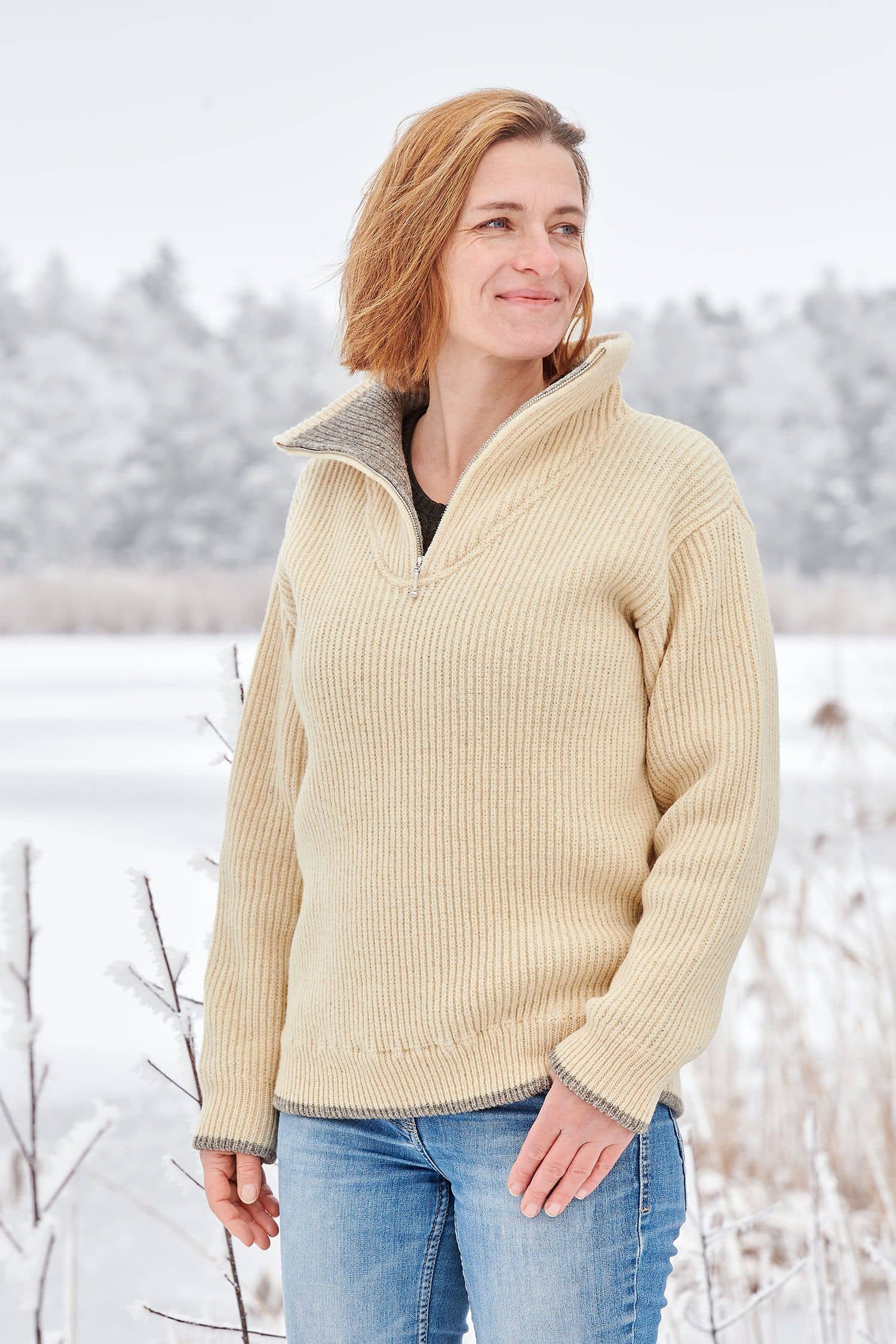 Frau in Schneelandschaft trögt einen naturweißen Finkhof Troyer aus bio Wolle (kbT)