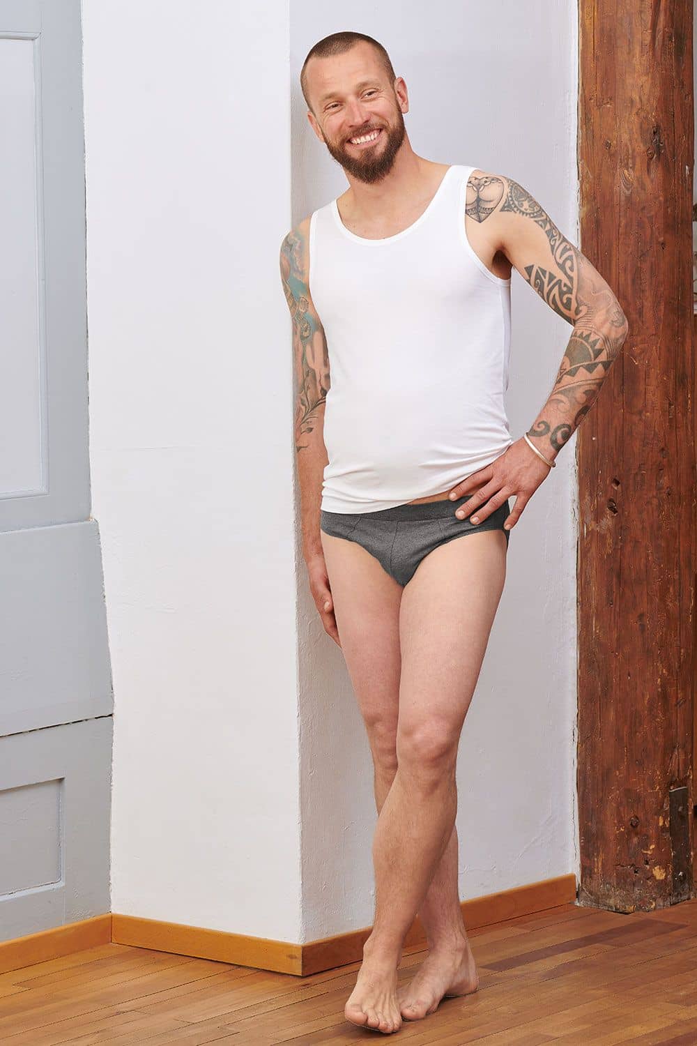 Baumwoll-Herren-Achselhemd weißes Herren Unterhemd aus bio Baumwolle (kbA) und Elasthan getragen mit Unterhose vor Holzbalken