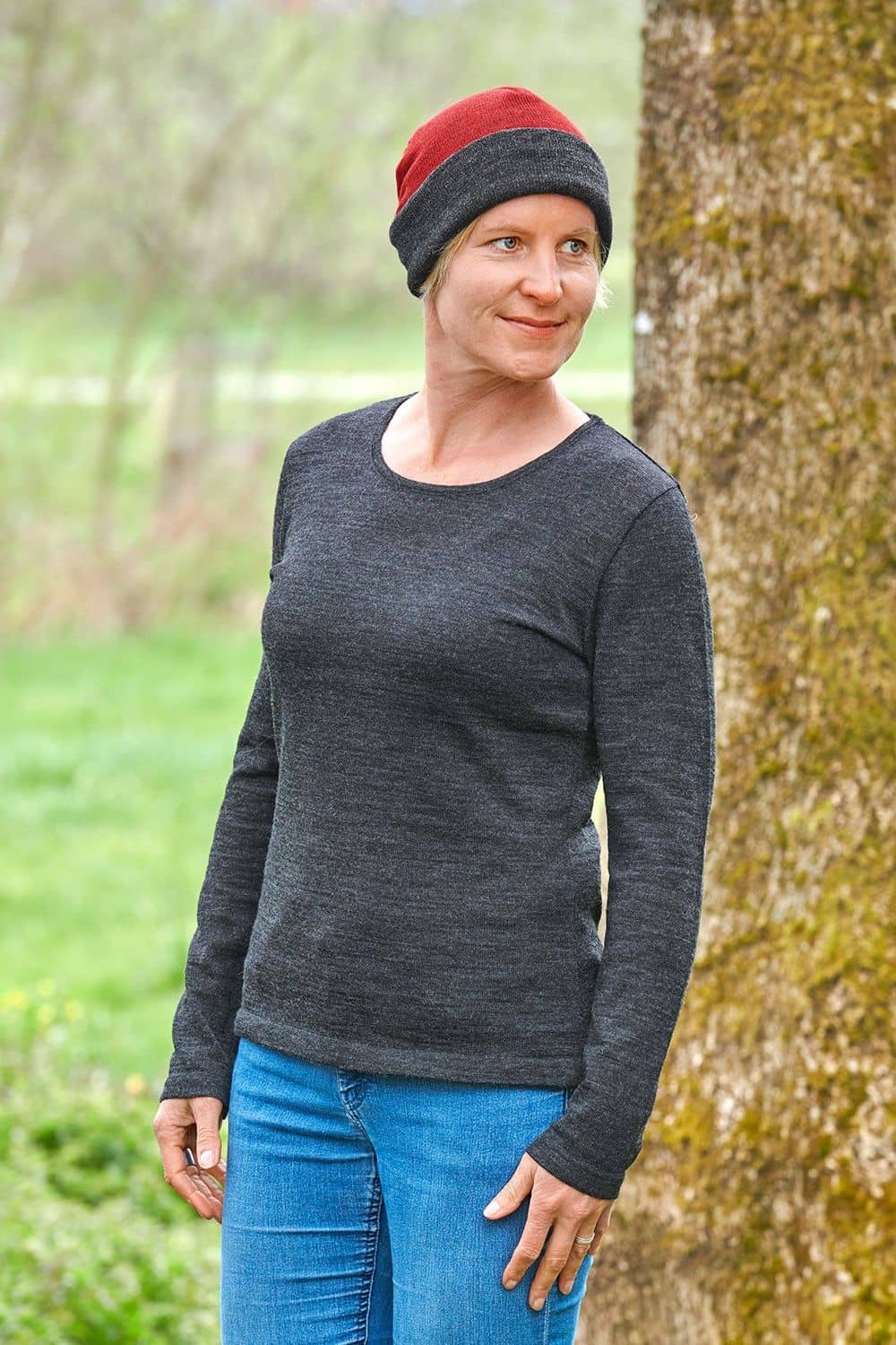 Frau mit grauem Shirt trägt anthrazitgraue/ rote Wendemütze aus bio Wolle (kbT) vom Finkhof