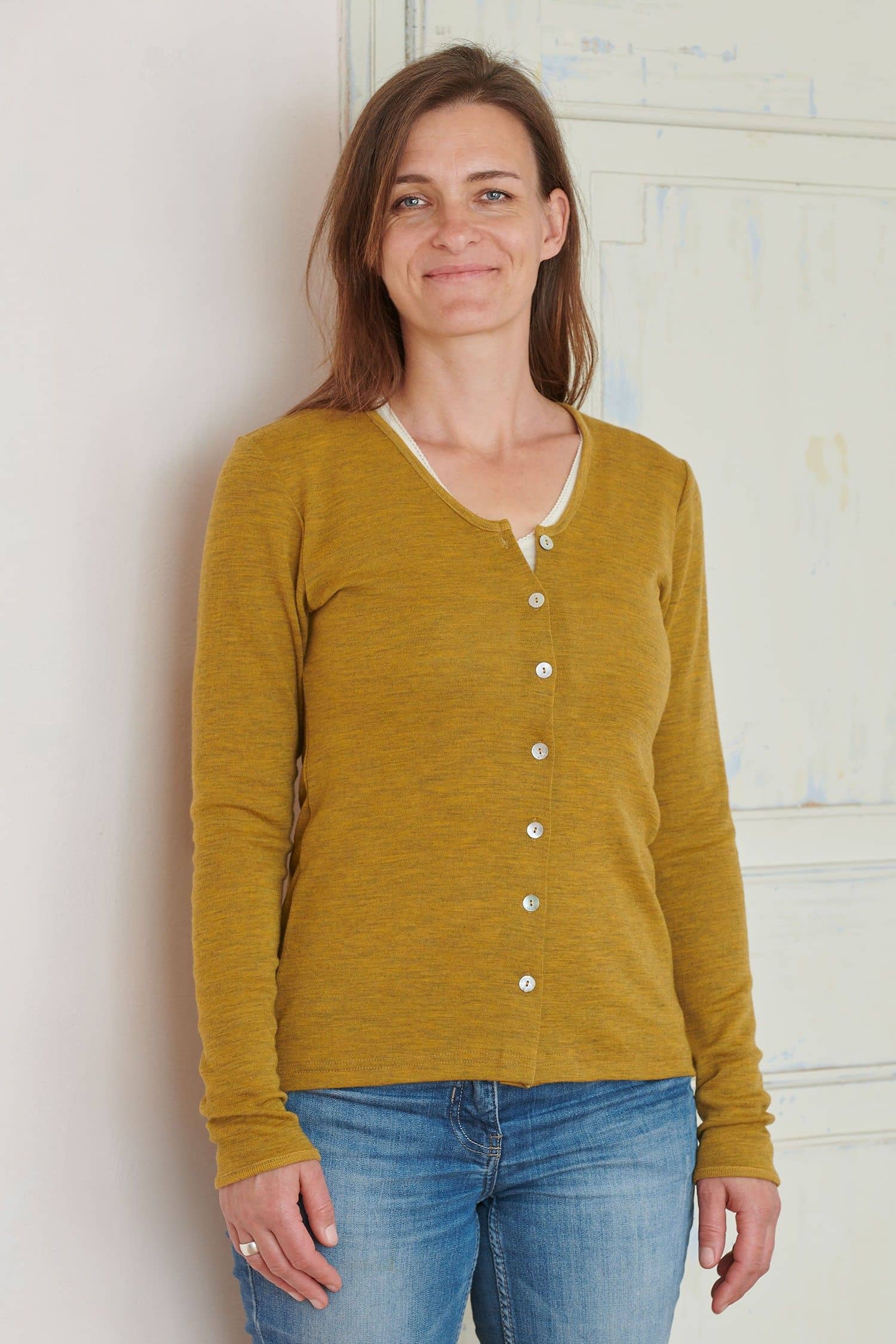 Frau trägt gelbmelierten Cardigan aus bio Wolle (kbT) und Jeans