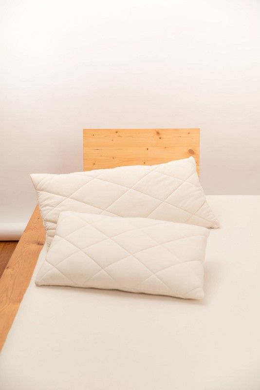 Steppkissen Finkhof Steppkissen aus bio Wolle (kbT) und bio Baumwolle (kbA) auf Holzbett mit hellem Laken