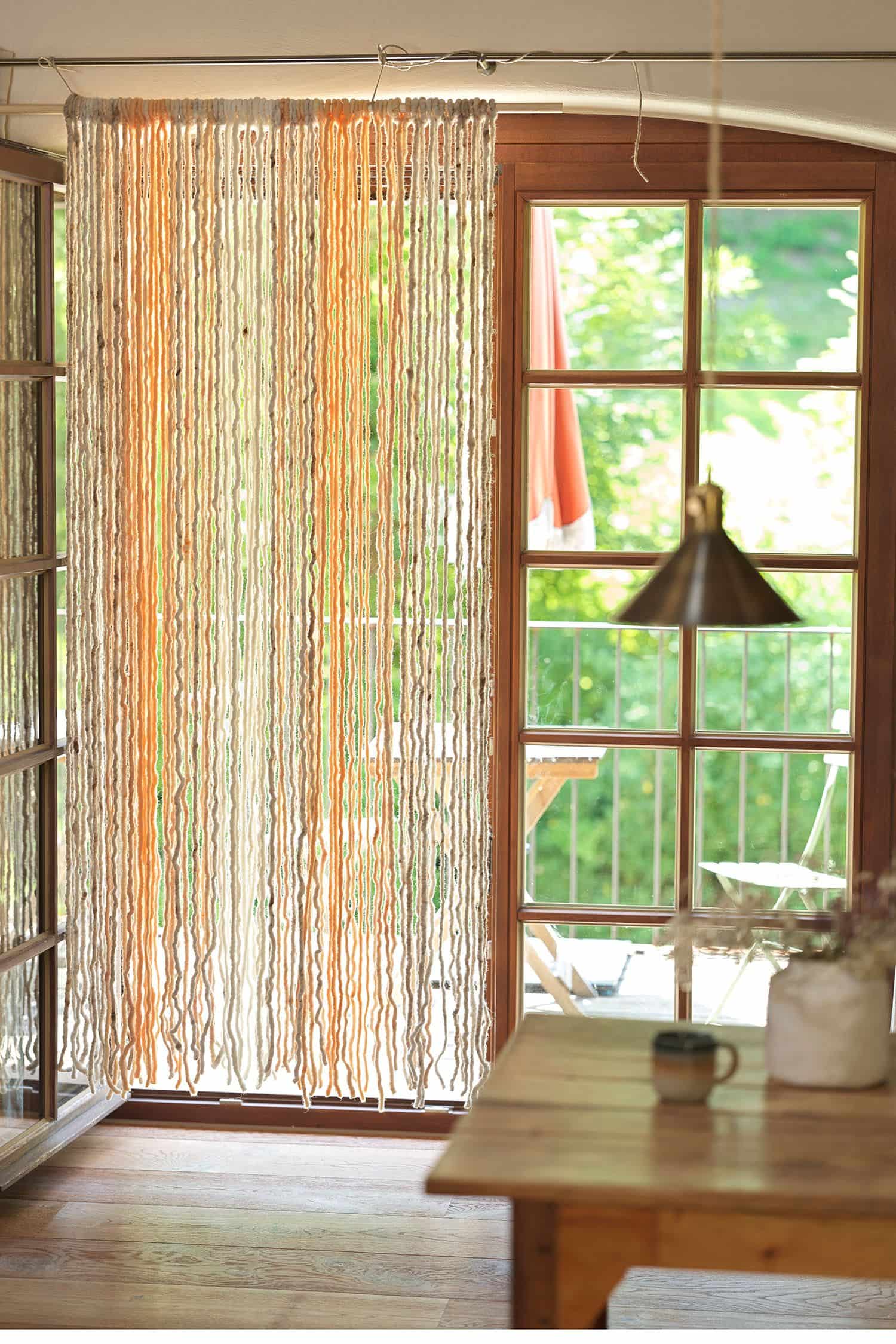 heller Finkhof Türvorhang aus Wolle und Jute hängt im Durchgang zum Balkon