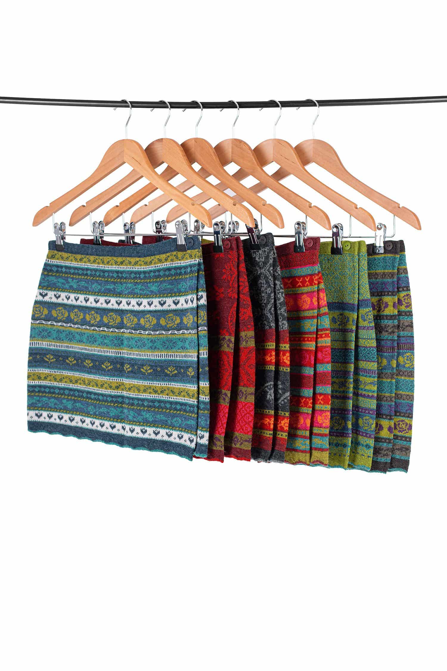 Cacheur gemustert sechs gemusterte Cacheurs aus bio Wolle (kbT) hängen mit Holzkleiderbügeln auf Kleiderstange, weißer Hintergrund