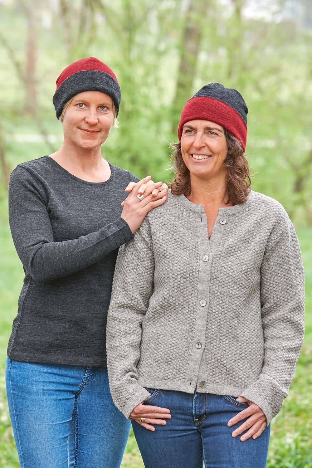 Frauen mit grauen Oberteilen tragen rote/ anthrazitgraue Wendemützen aus bio Wolle (kbT) vom Finkhof