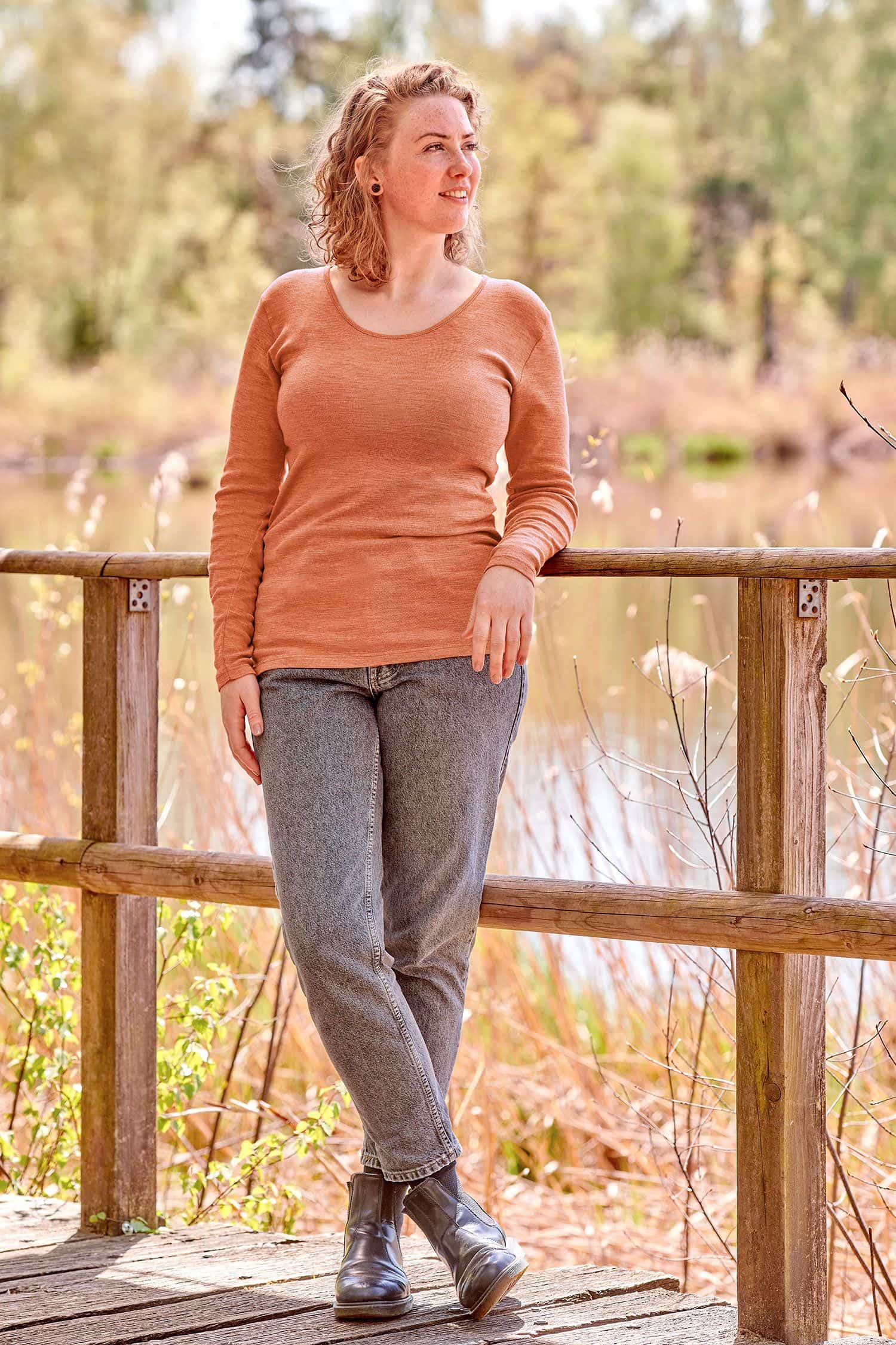 Frau mit grauer Jeans trägt oranges Langarmshirt aus bio Wolle (kbT), bio Baumwolle (kbA) und Seide