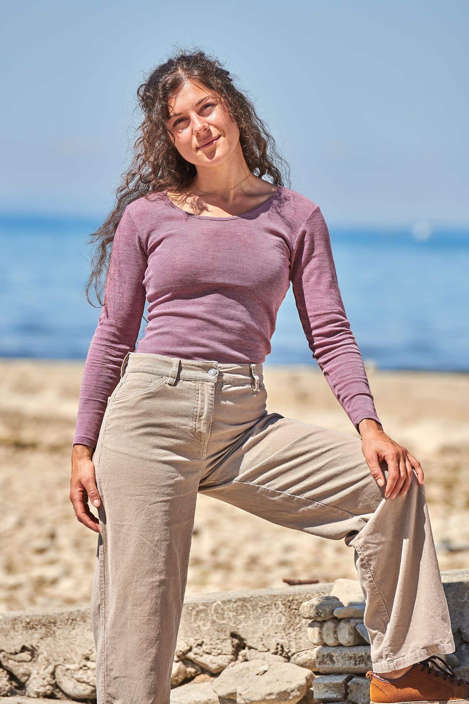 Frau trägt ein lilafarbenes Langarmshirt aus bio Baumwolle (kbA), bio Wolle (kbT) und Seide und eine beige Jeans