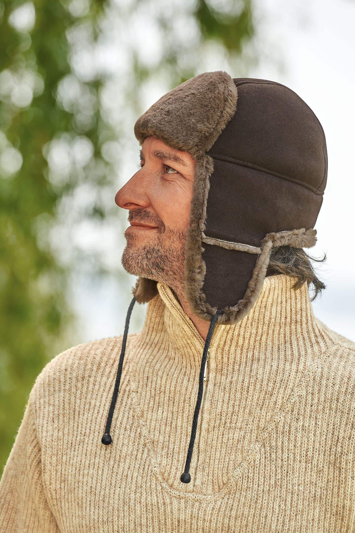 Mann mit Finkhof Troyer trägt eine braune Fellmütze aus Schaffell vom Finkhof