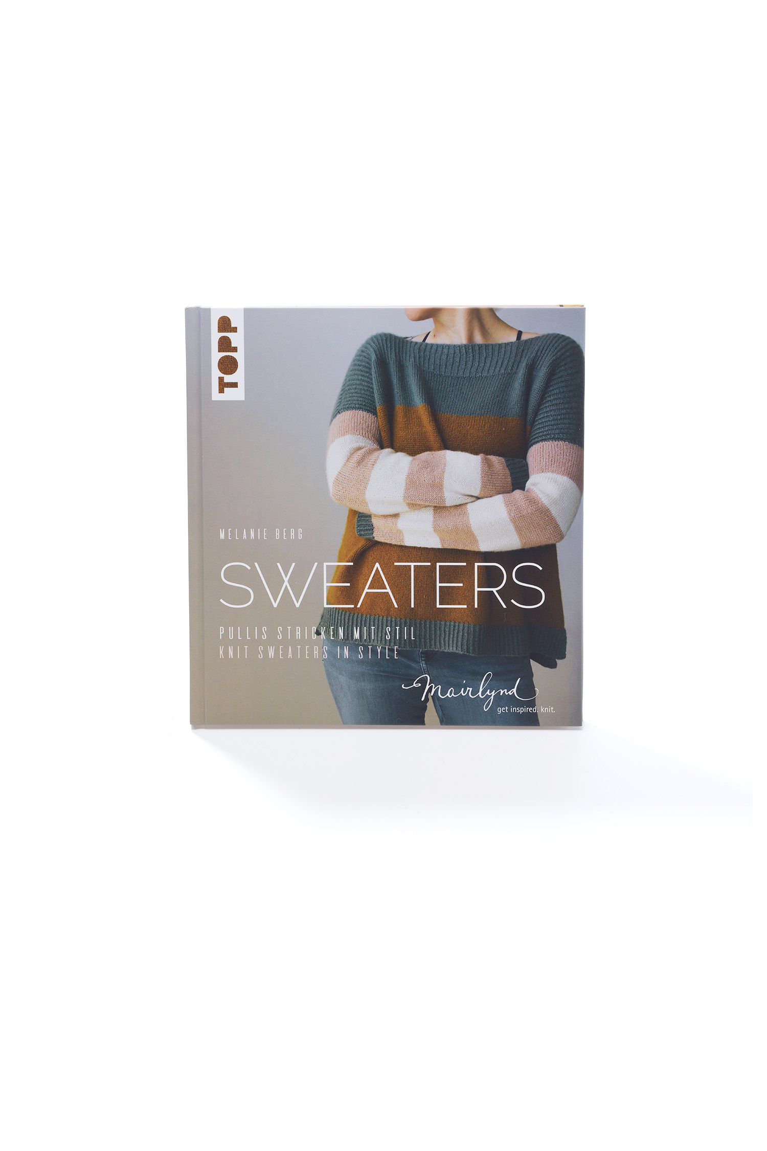 Buch ,,Sweaters - Pullover stricken mit Stil" vor Holzwand, darunter ein beiger Strickpulli