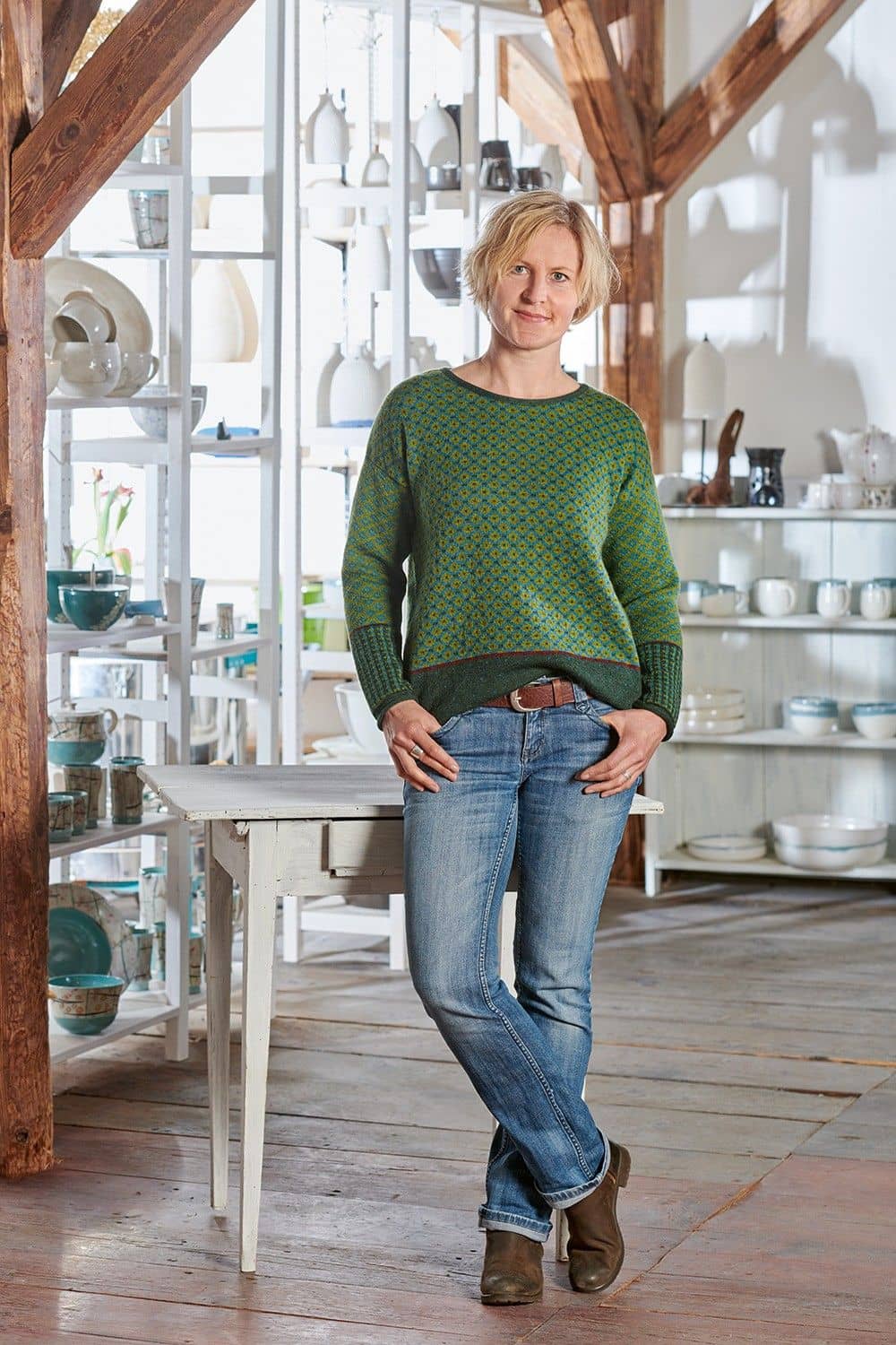 Frau mit Jeans trägt grün türkis gemusterten Pulli aus bio Wolle (kbT)