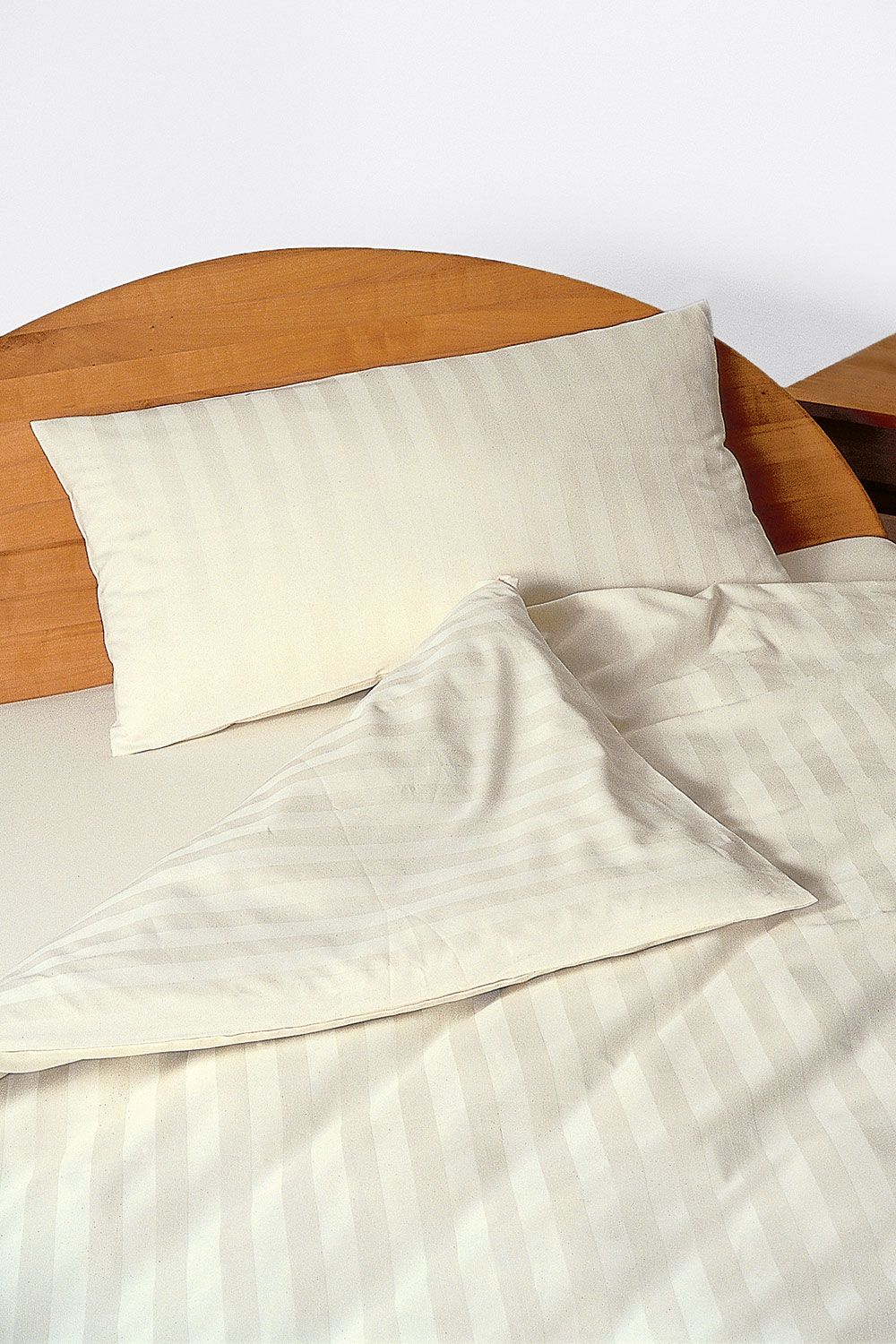 Bettwäsche „Streifen" naturweiß Bettwäsche naturweiß mit Streifen aus bio Baumwolle (kbA) mit Kopfkissen und Decke in braunem Holzbett