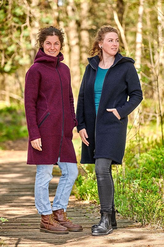 Wollmantel zwei Frauen stehen auf einem Pfad und tragen Wollmäntel in beere und marineblau dazu Jeans und Stiefel
