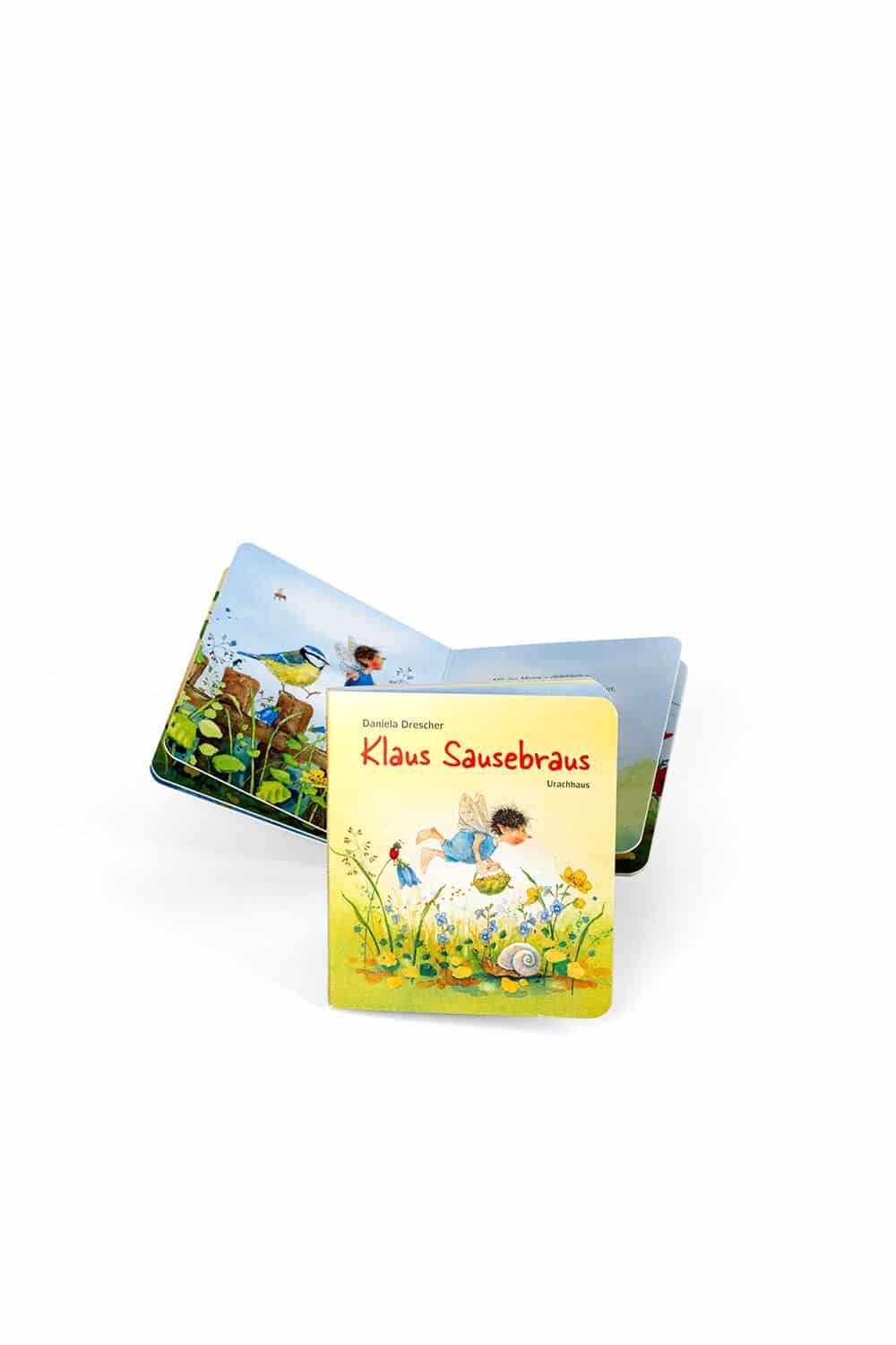 Buch ,,Klaus Sausebraus" auf weißem Untergrund mit aufgeschlagenem Exemplar dahinter
