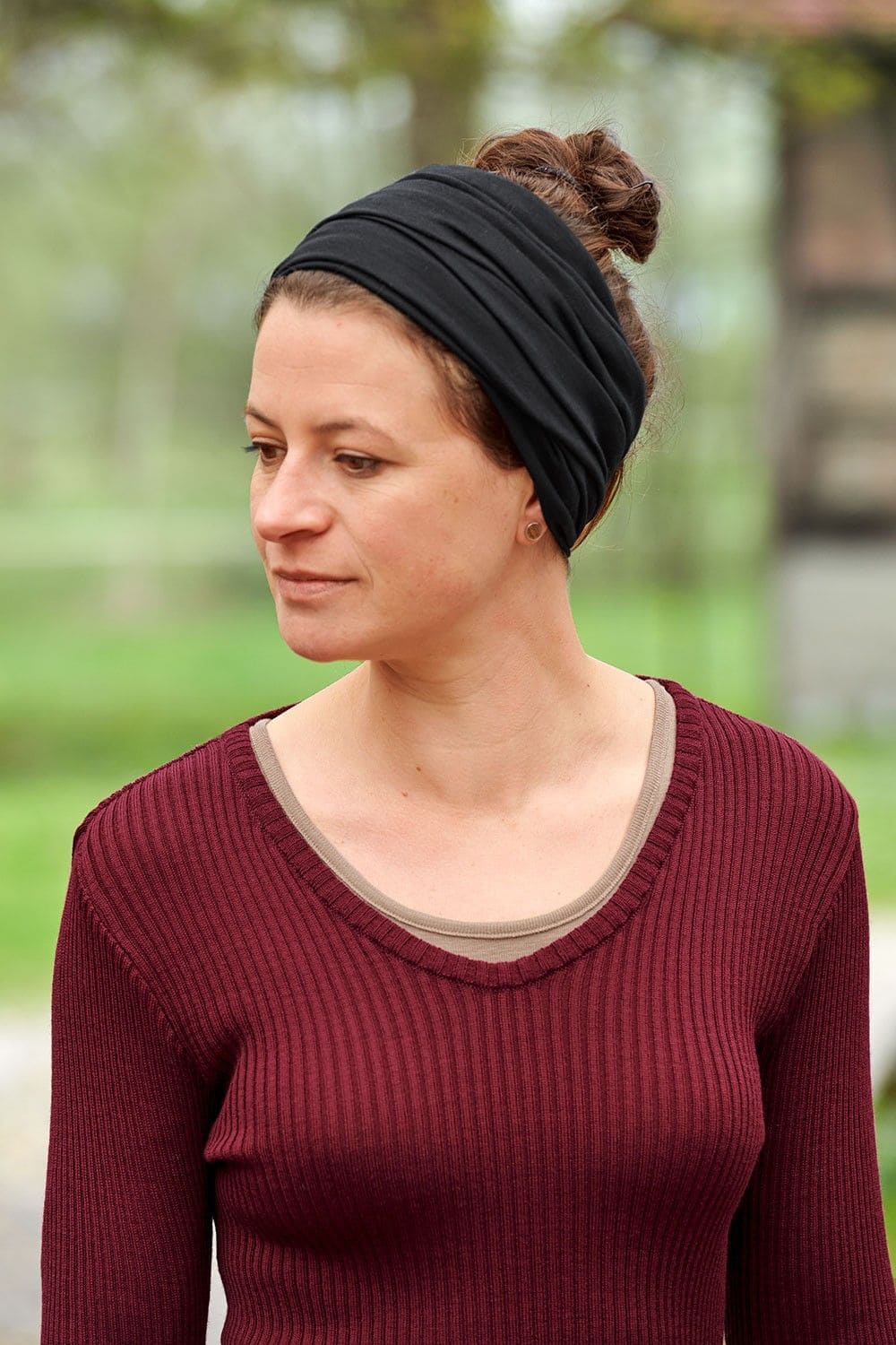 Frau mit rotem Rippshirt trägt einenn schwarzen Sportschal aus bio Wolle (kbT) und Seide als Stirnband