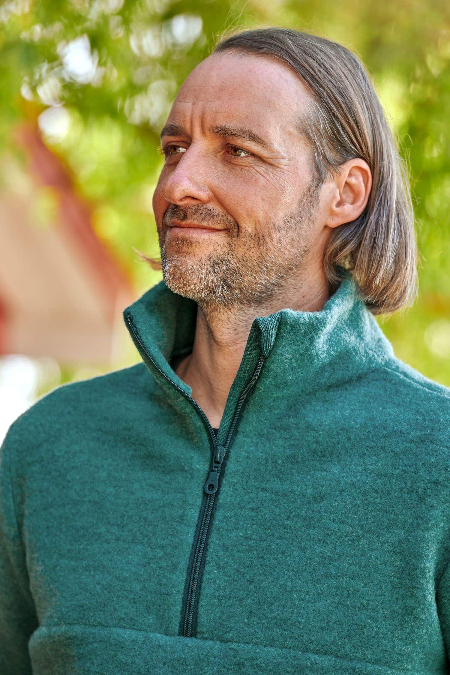 Portraitaufnahme von Mann mit türkisem Pulli mit hohem Kragen und Reißverschluss aus bio Wolle (kbT) vom Finkhof