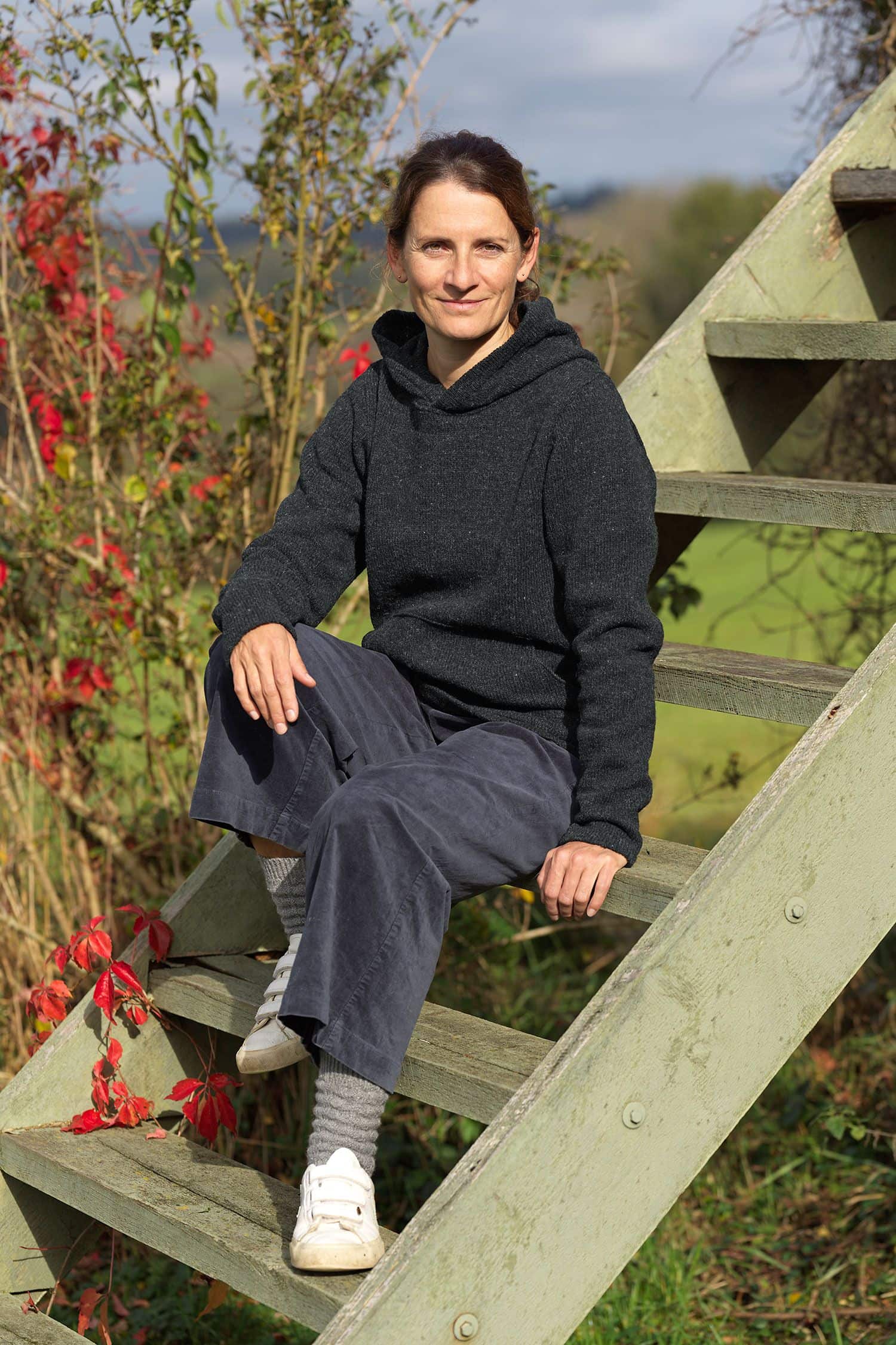 Frau sitzt auf Treppe und trägt dunkelgrauen Kapuzenpulli aus bio Wolle (kbT) vom Finkhof