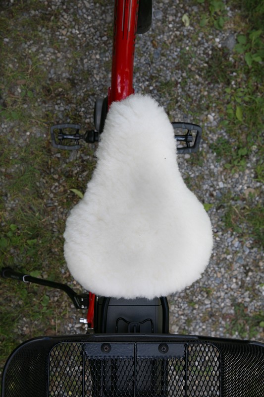 Fahrradsattelbezug breit mit Schaffell schmaler weißer pflanzlich gegerbter Sattelbezug vom Finkhof aus bio Wolle (kbT) und Schaffell auf rotem Fahrrad von oben