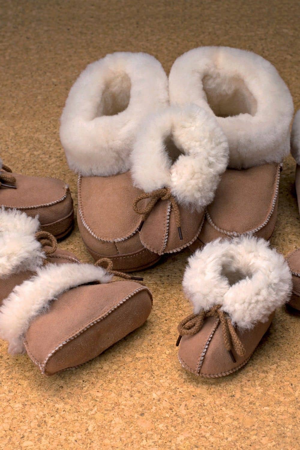 Fellschuhe für Kinder Kinder Fellschuhe von Gottstein aus Schaffell in Braun und Weiß, verschiedene Größen vor braunem Hintergrund