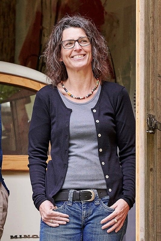 Frau trägt graues Shirt und schwarzer Cardigan mit Knöpfen aus bio Wolle (kbT) und Elasthan