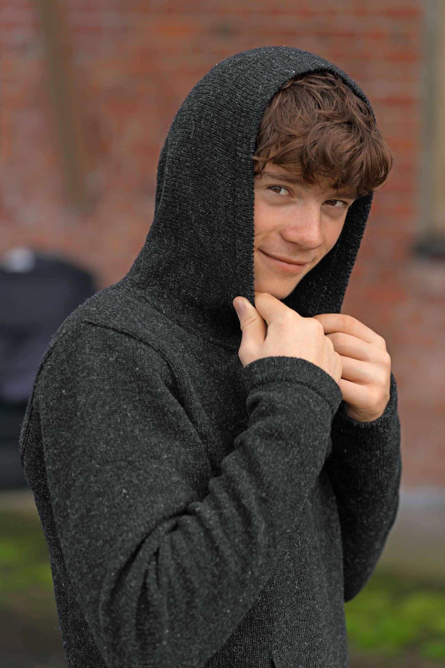 Junge trägt anthrazitfarbenen Pulli mit Kapuze aus bio Merinowolle (kbT) vom Finkhof