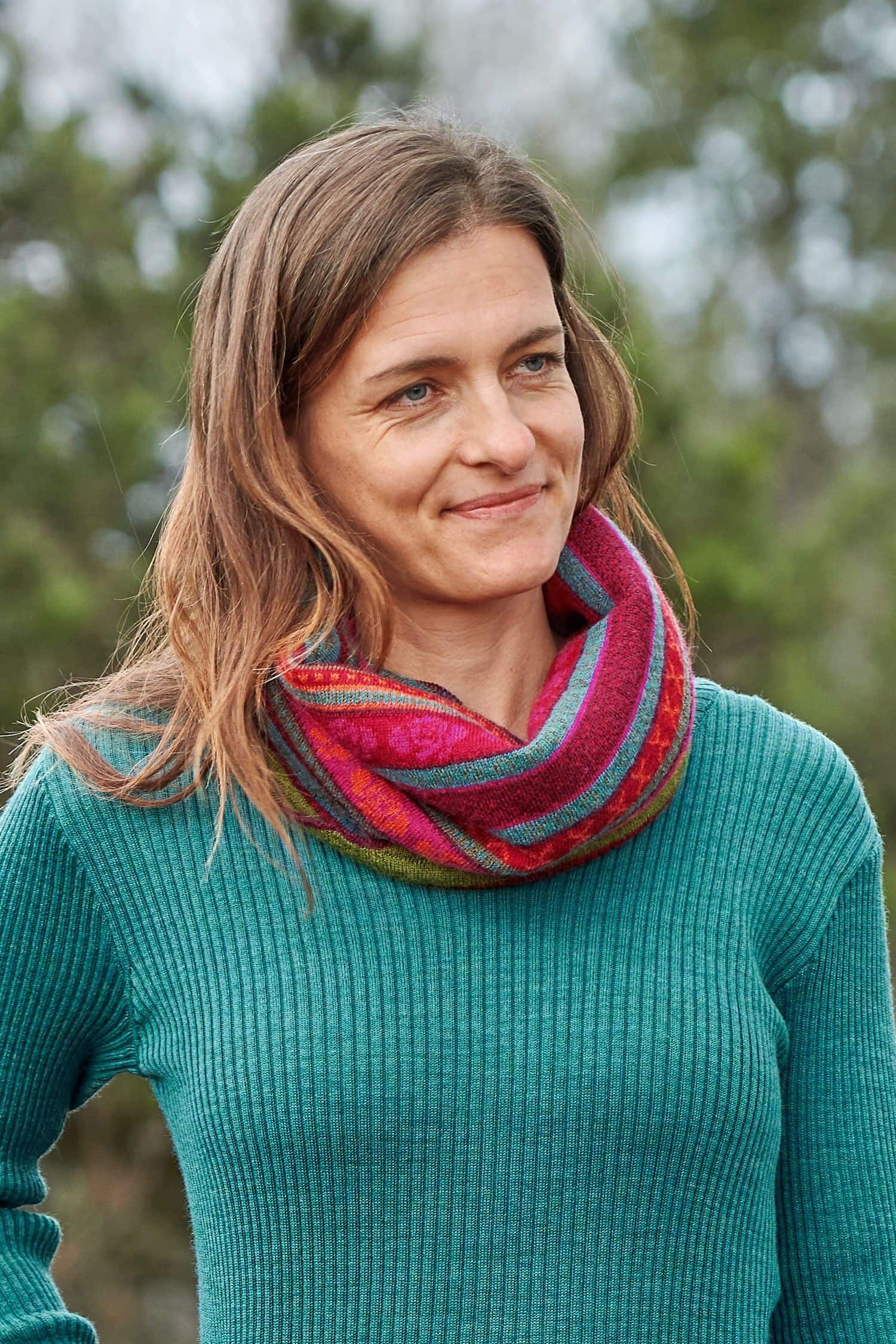 Loop gemustert Konfetti Frau mit türkisem Rippshirt trägt rötlich gemusterten Loopschal aus bio Wolle (kbT)