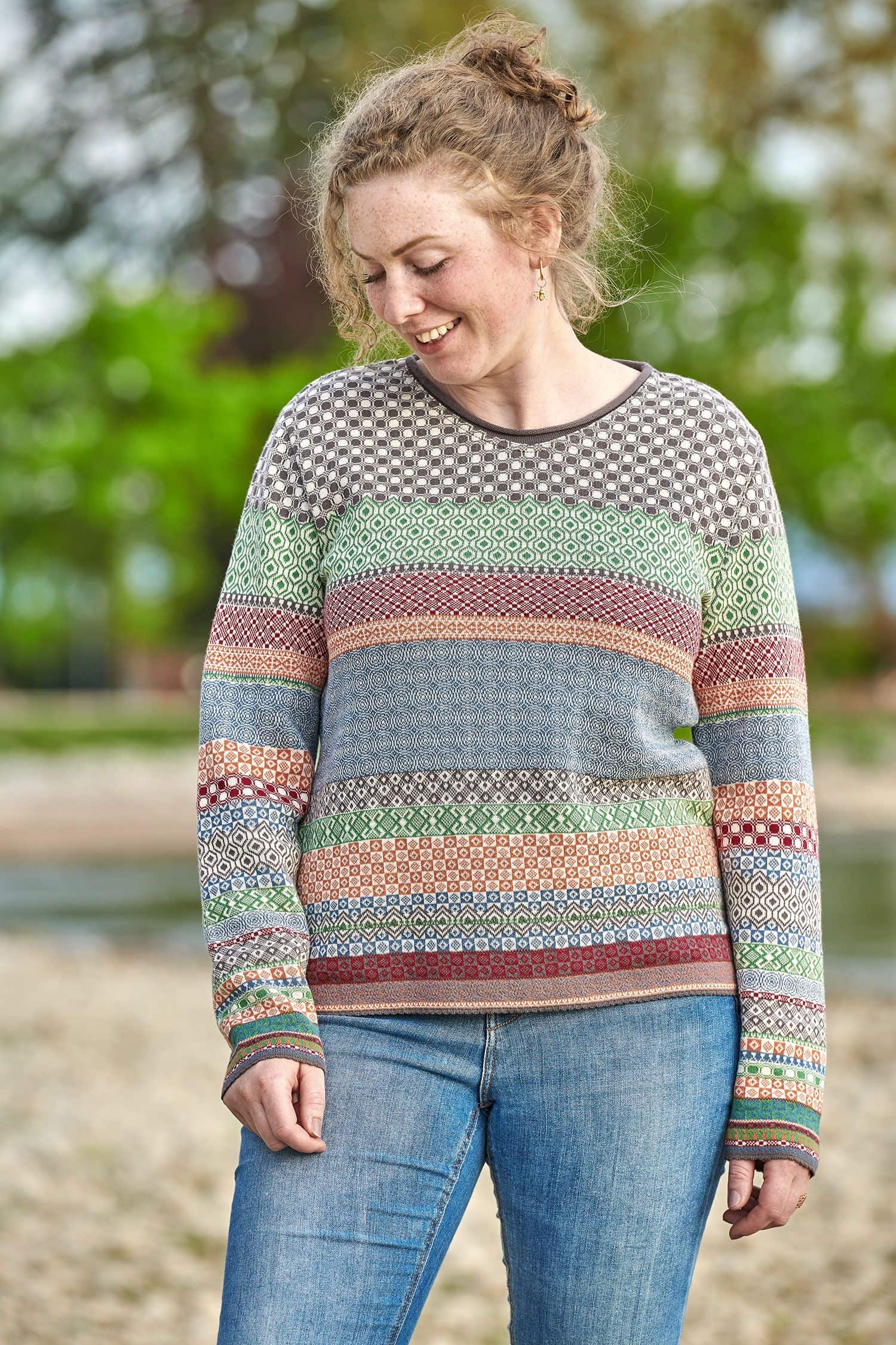 Frau trägt eine Jeans und einen gemusterten Strickpullover aus bio Baumwolle (kbA)