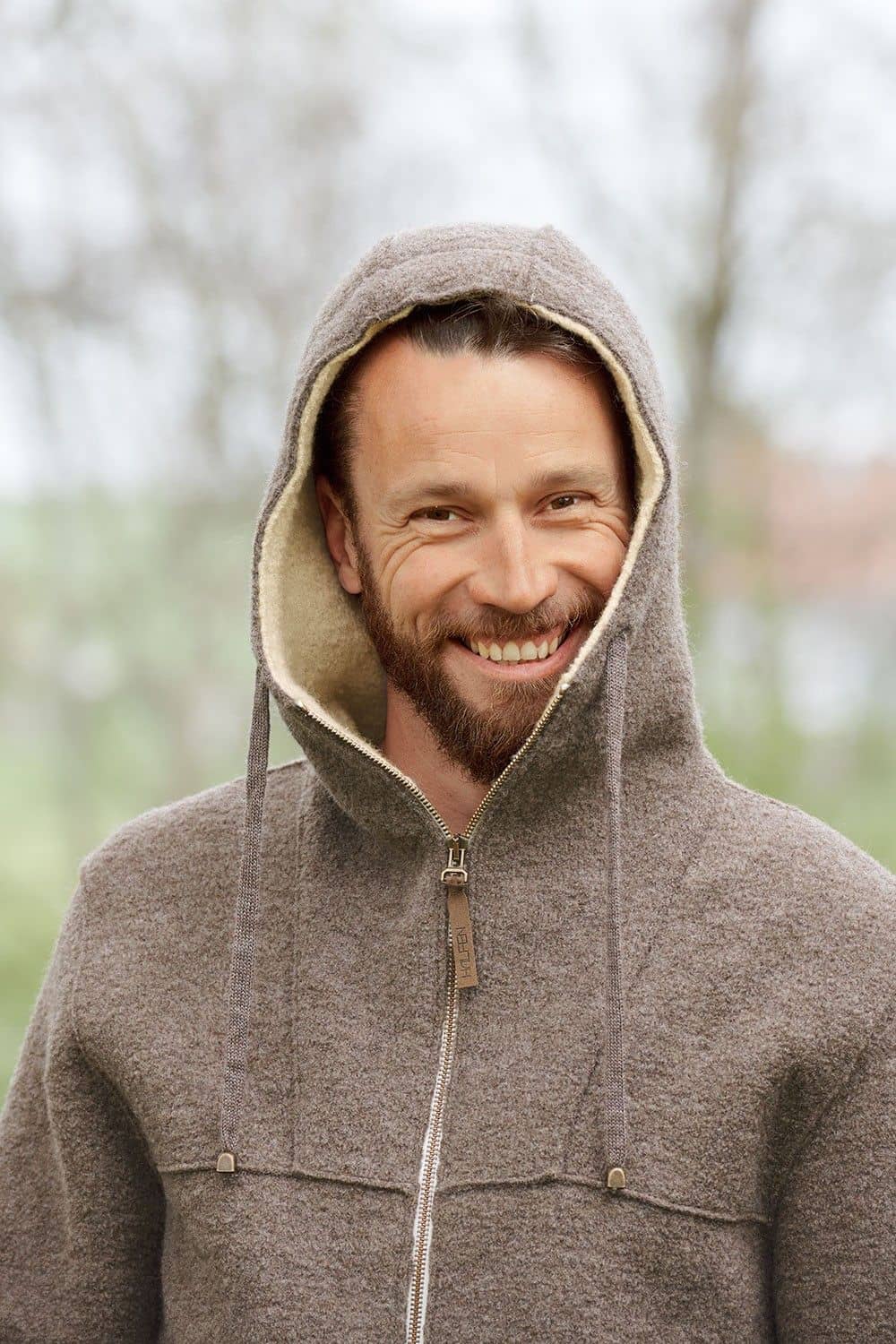 Mann hat die Kapuze der braunen Finkhof Jacke aus bio Wolle (kbT) auf