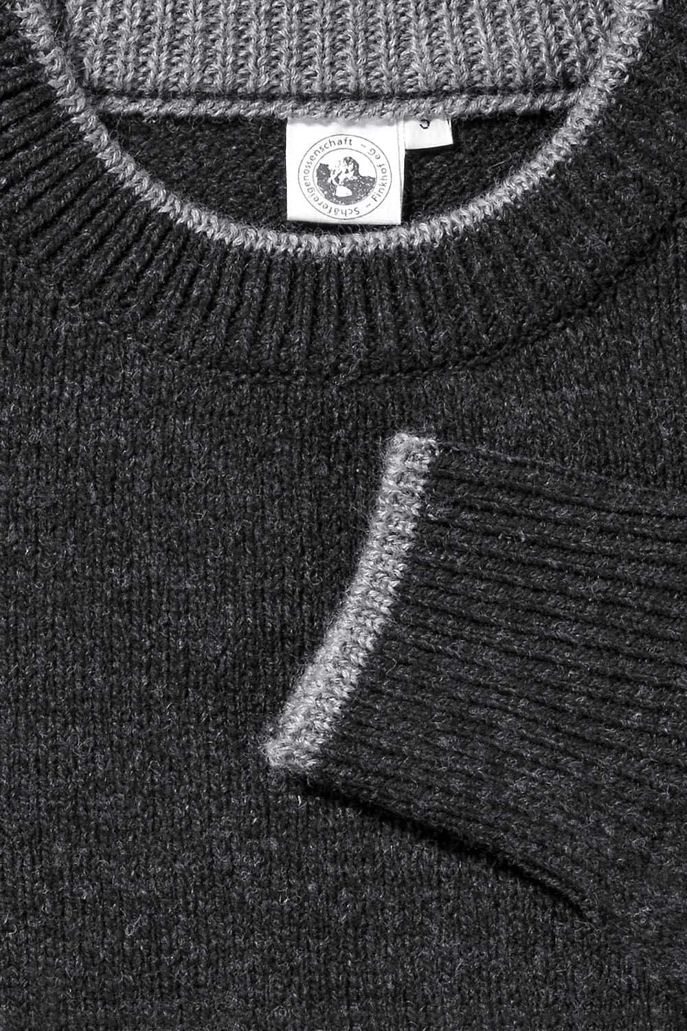 Detailaufnahme der hellgrauen Kanten des anthrazitgrauen Finkhof Pullis aus bio Wolle (kbT)