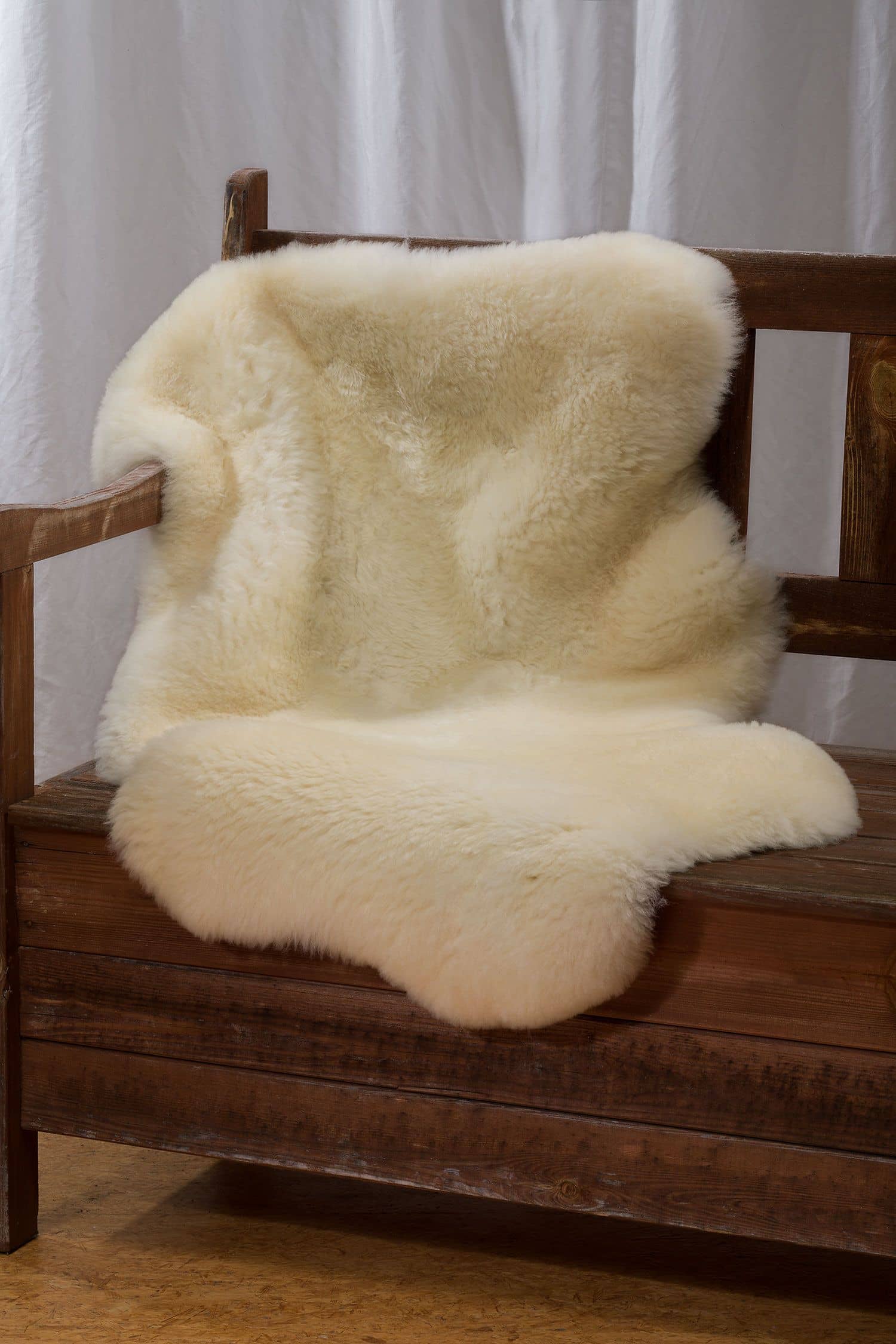 Schaffell pflanzlich weiß Gr. L (groß) Schaffell Größe L (101–115?cm) in Weiß vom Finkhof – naturbelassen, pflanzlich gegerbt, auf Holzstuhl als Sitzauflage gezeigt