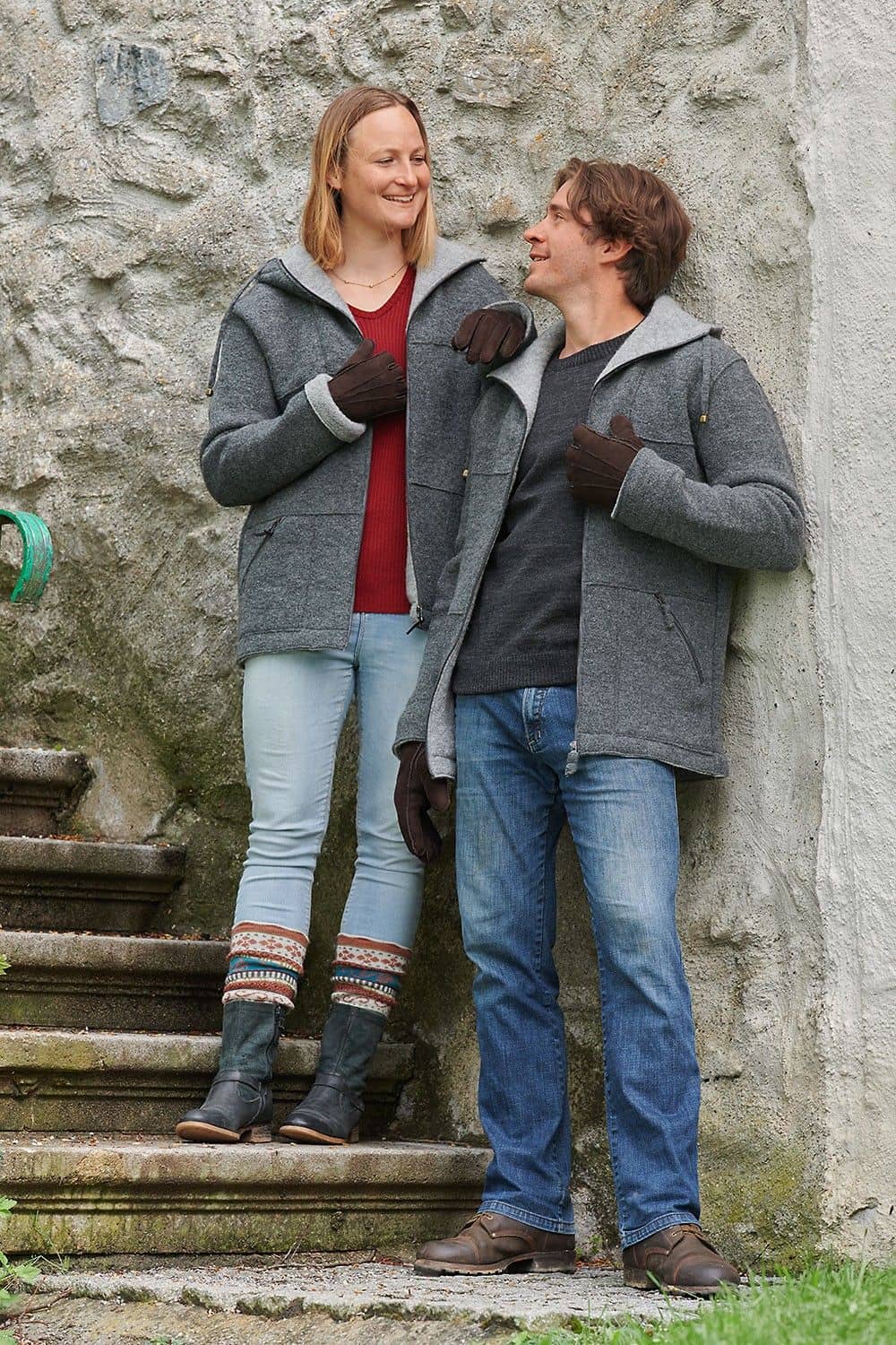 Mann und Frau mit grauen Jacken stehen auf Treppe und tragen dunkelbraune Fell-Fingerhandschuhe aus Pelzvelour