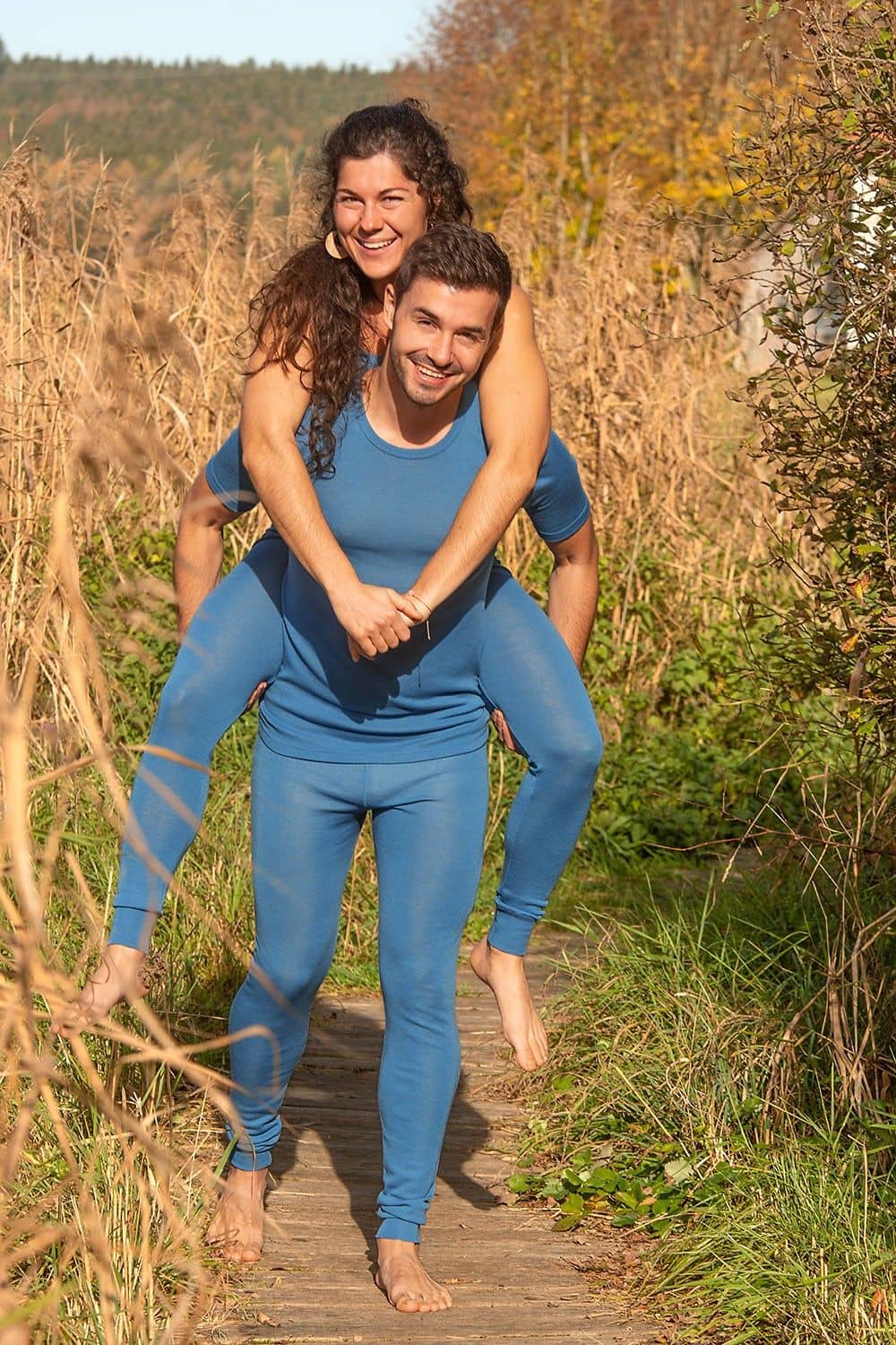 Mann nimmt Frau Huckepack, biede tragen blaue lange Unterhosen aus bio Wolle (kbT) mit Shirt und Top