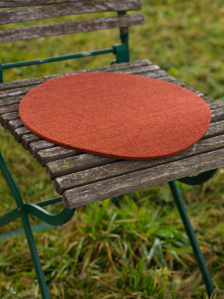 orange runde Finkhof Sitzauflage aus bio Wolle (kbT) auf einem Gartenstuhl