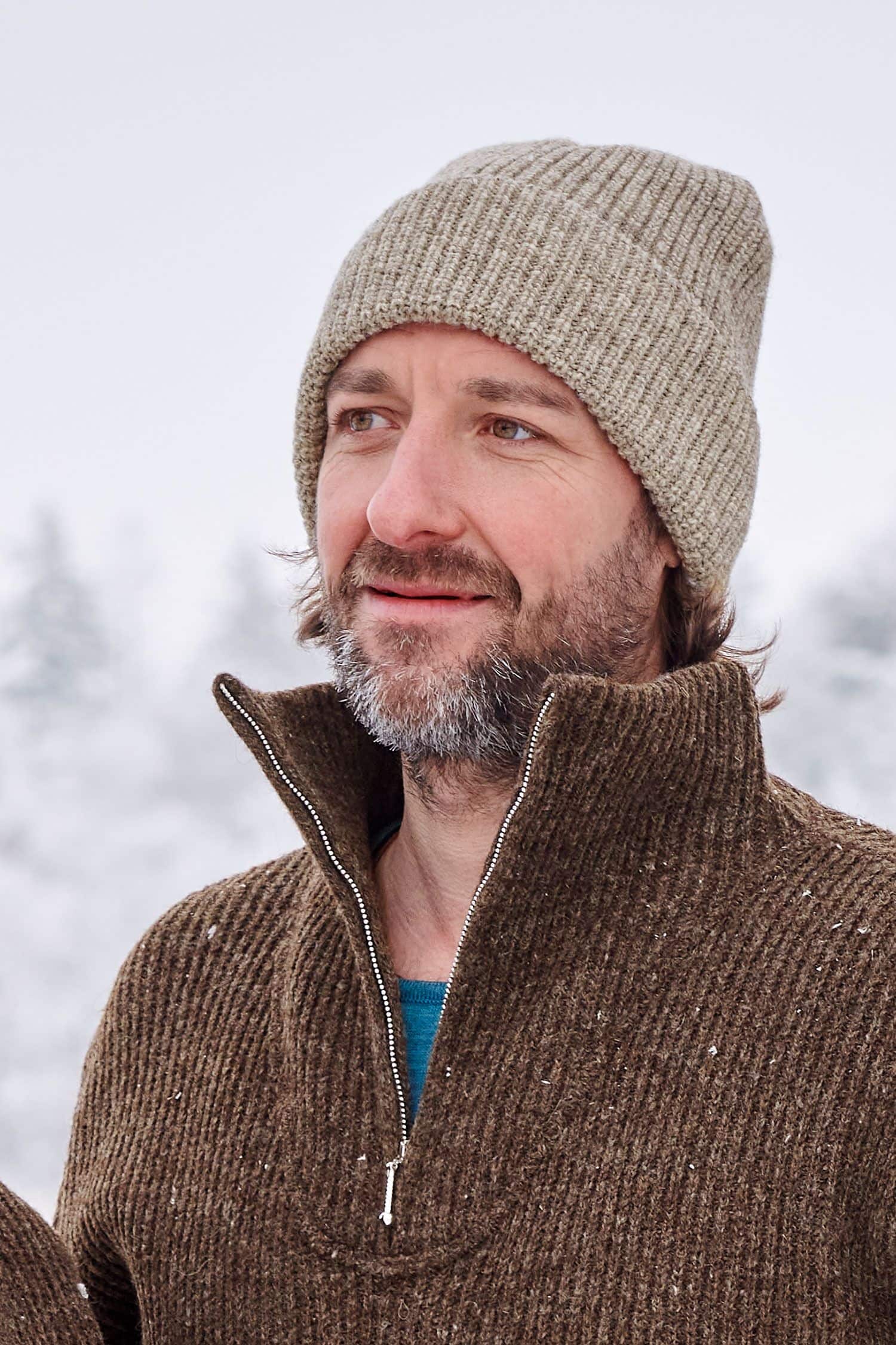 Mann trägt graue Finkhof Mütze aus bio Wolle (kbT) und braunen Finkhof Troyer