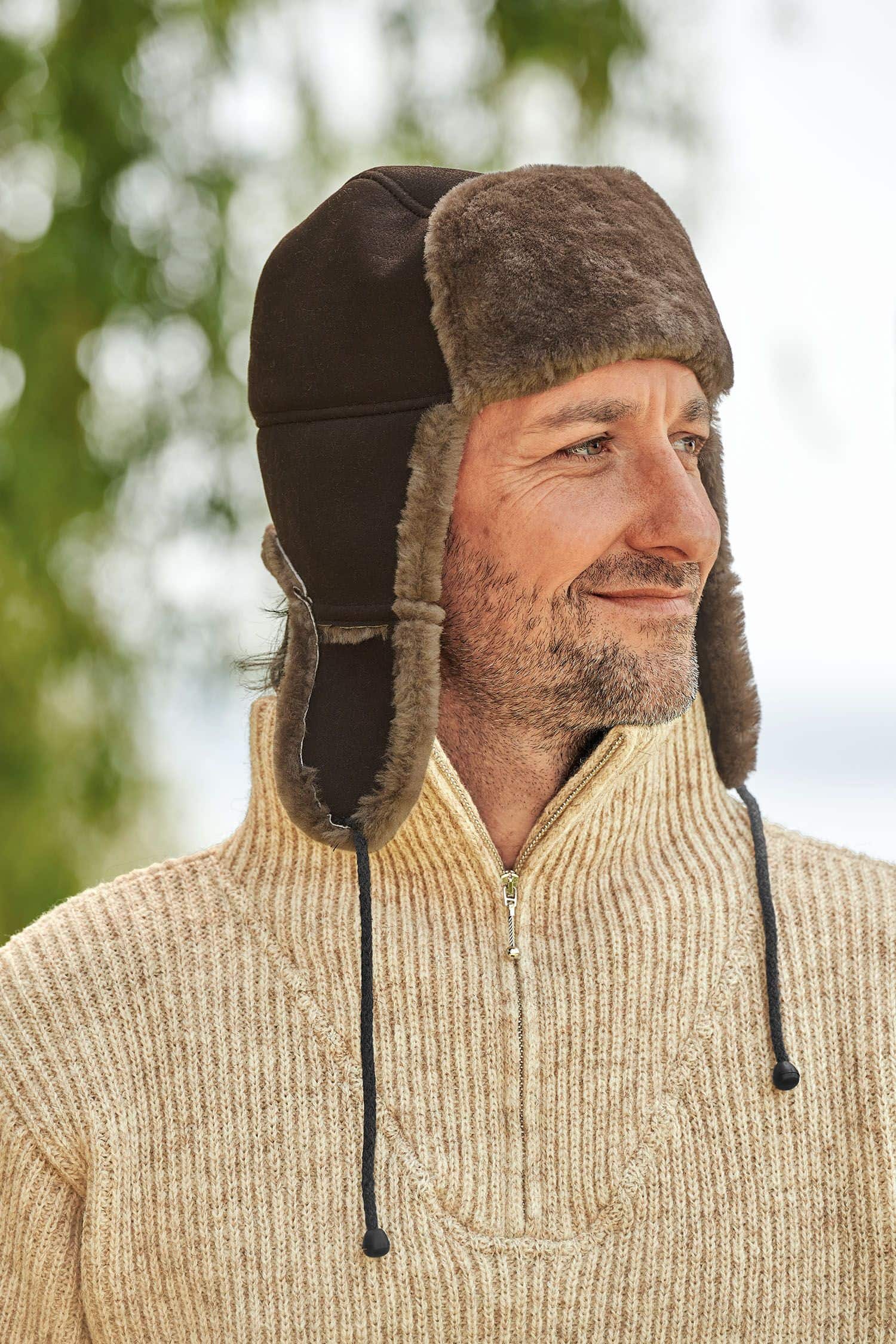 Mann mit Finkhof Troyer trägt eine braune Fellmütze aus Schaffell vom Finkhof