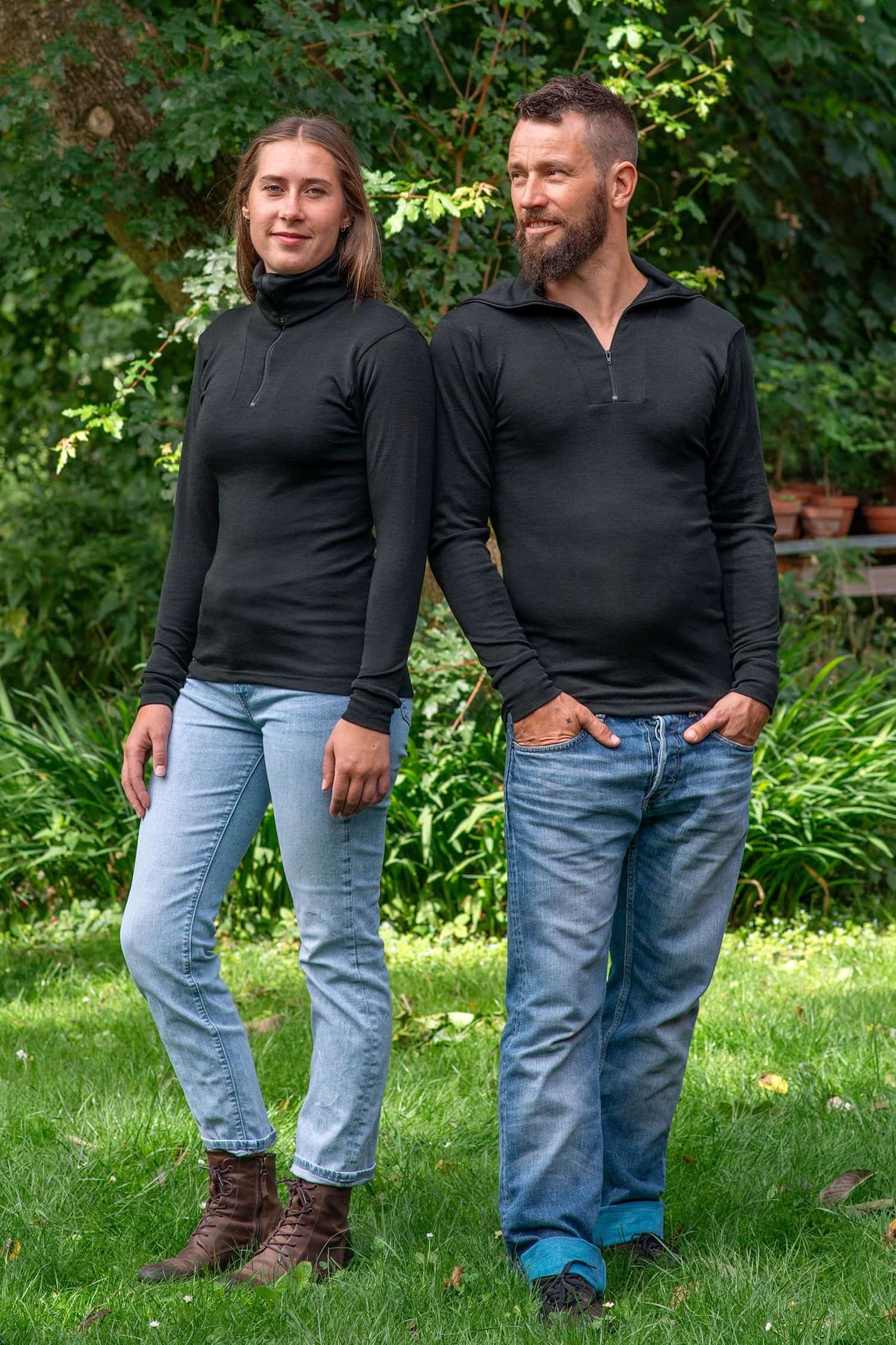 Mann und Frau im Garten tragen Jeans und schwarzen Sportrolli aus bio Wolle (kbT) und Seide mit Reißverschluss