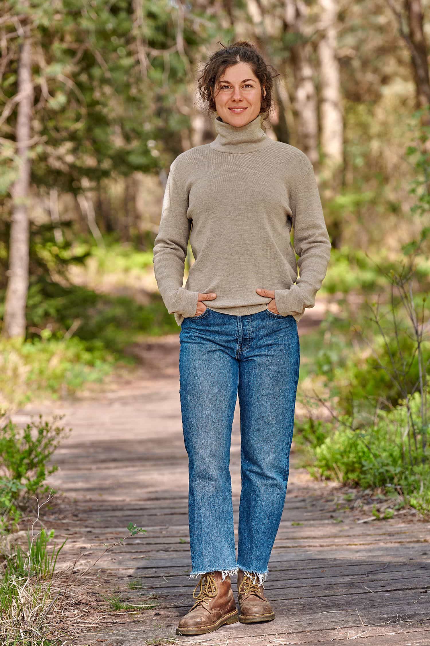 Frau trägt beigen Pullover mit Rollkragen aus bio Merinowolle (kbT) vom Finkhof und eineJeans