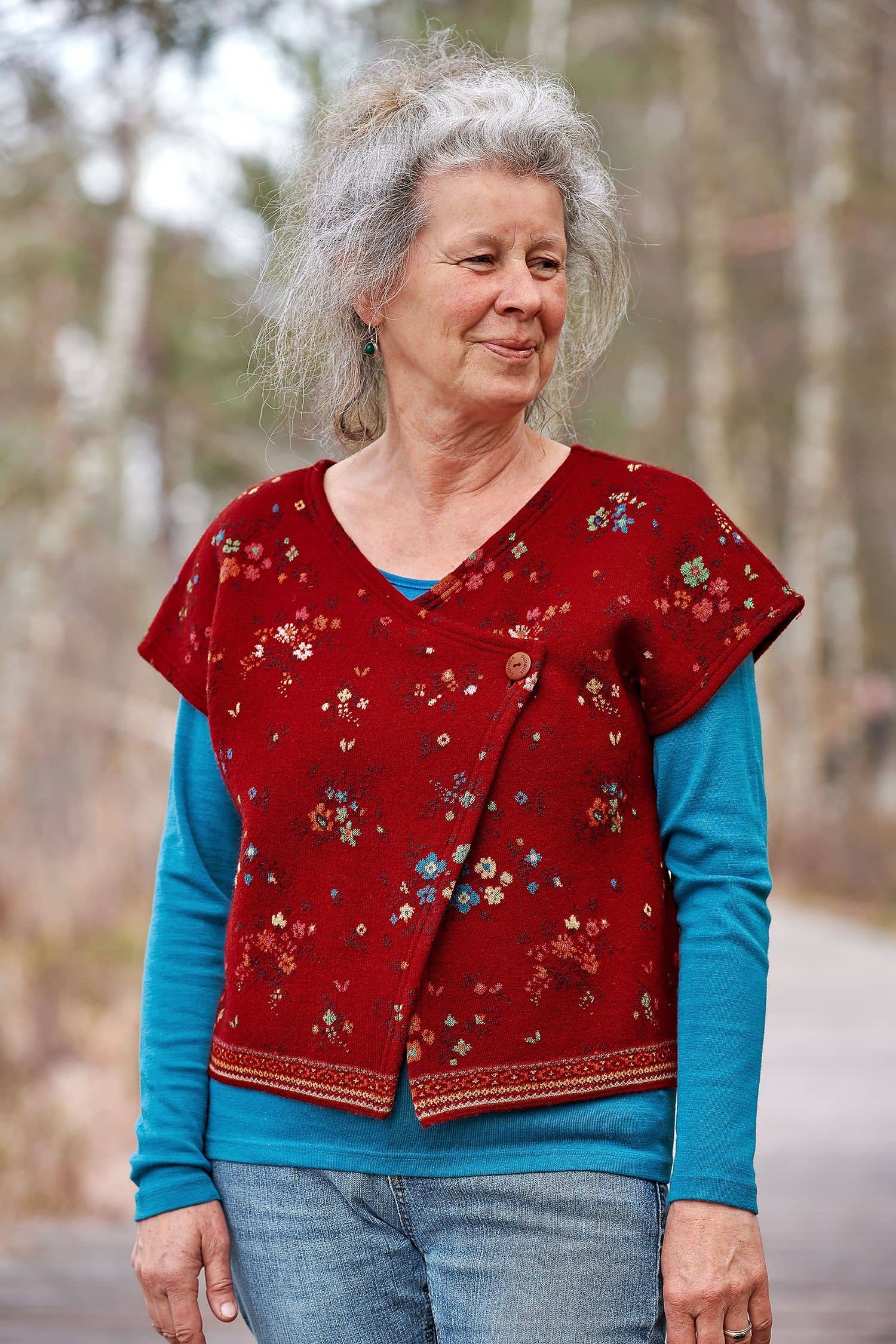 Frau mit blauem Shirt trägt Walk Kurzweste in rot mit floralem Muster aus bio Merinowolle (kbT) und Baumwolle (kbA)