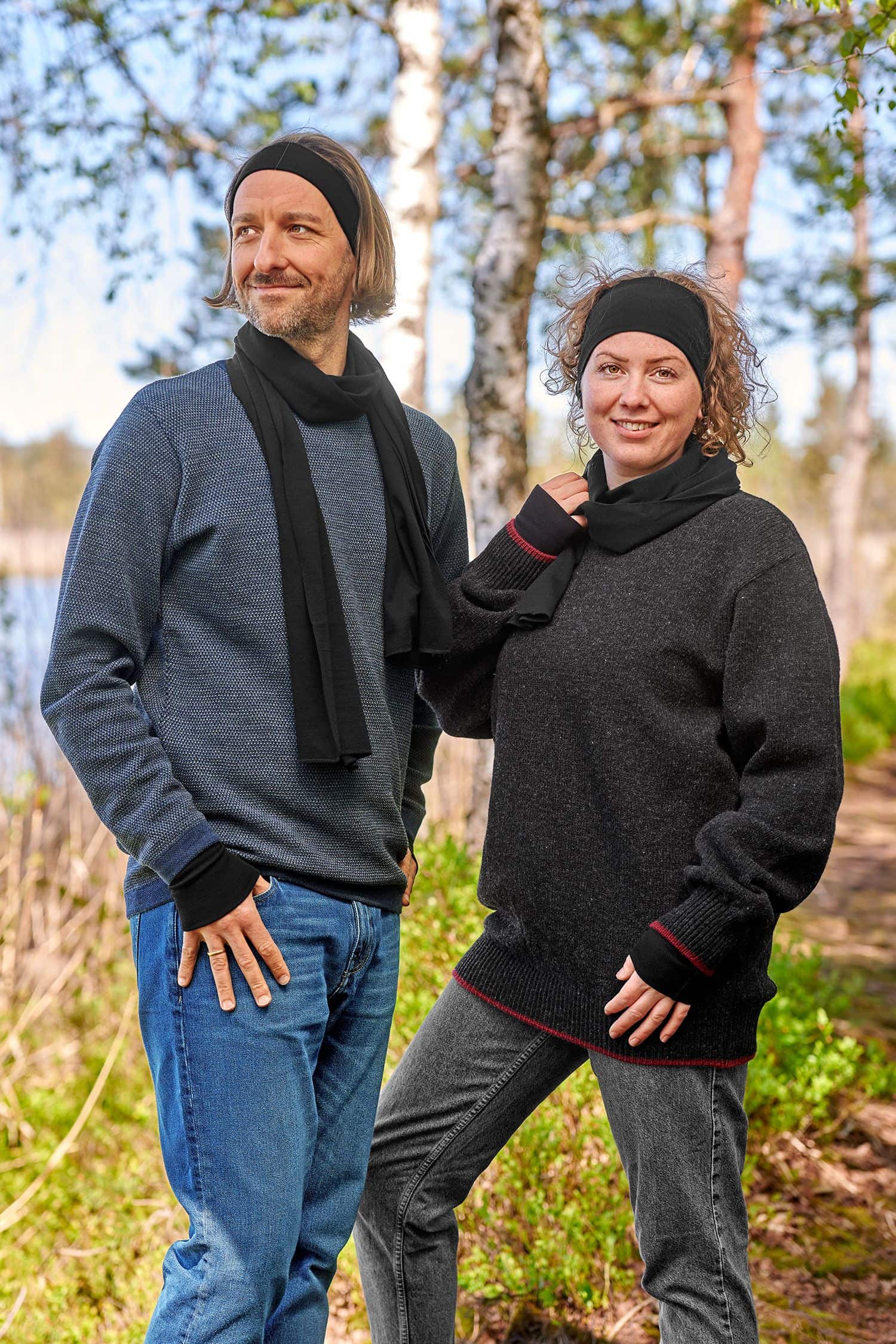 Mann und Frau mit dunklen Pullis tragen schwarze Stirnbänder, Schals und Pulswärmer aus bio Wolle (kbT) und Seide