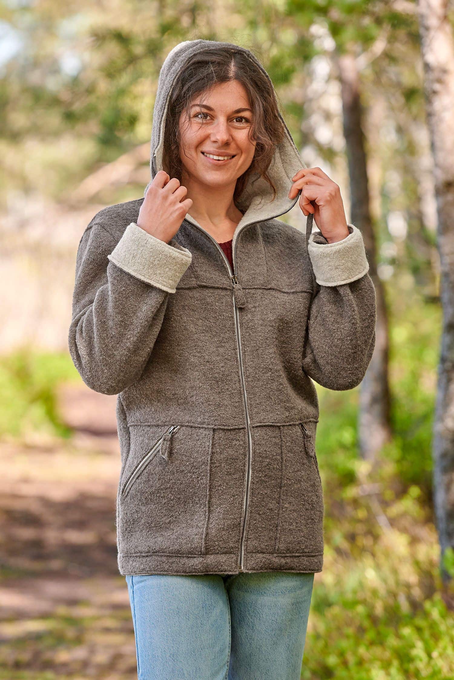 Frau setzt sich Kapuze von walnussbrauner Jacke aus bio Wolle (kbT) vom Finkhof auf