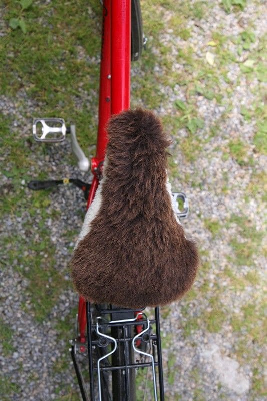 brauner schmaler pflanzlich gegerbter Sattelbezug vom Finkhof aus bio Wolle (kbT) und Schaffell auf rotem Fahrrad von oben