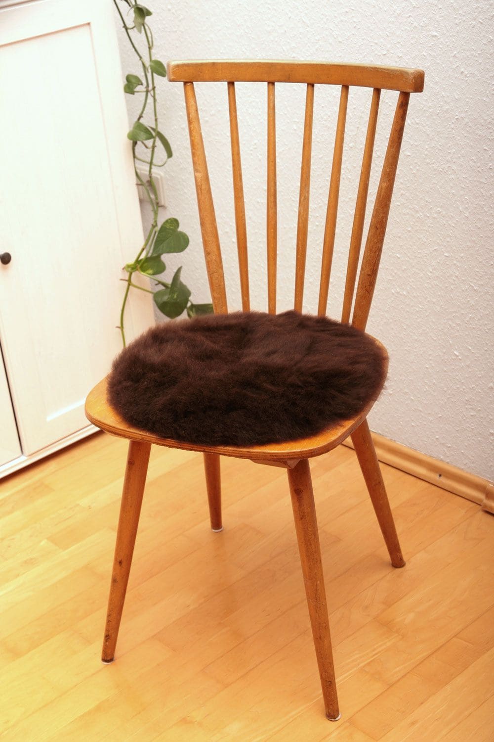pflanzlich gegerbte runde Stuhlauflage vom Finkhof aus braunem Schaffell auf braunem Holzstuhl